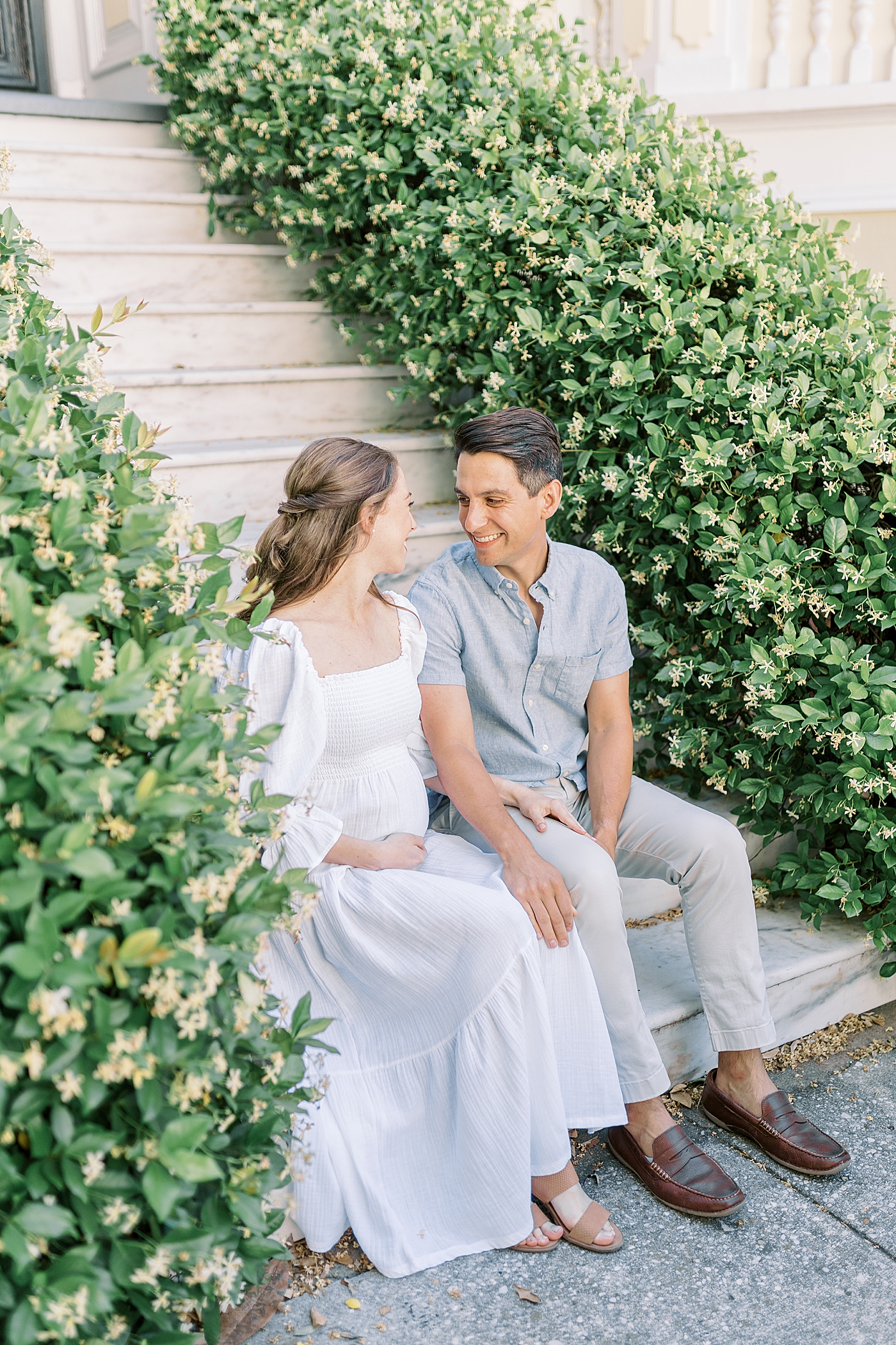 Mom and dad to be sitting on steps surrounded by jasmine | Photo by Charleston Film Photographer Caitlyn Motycka