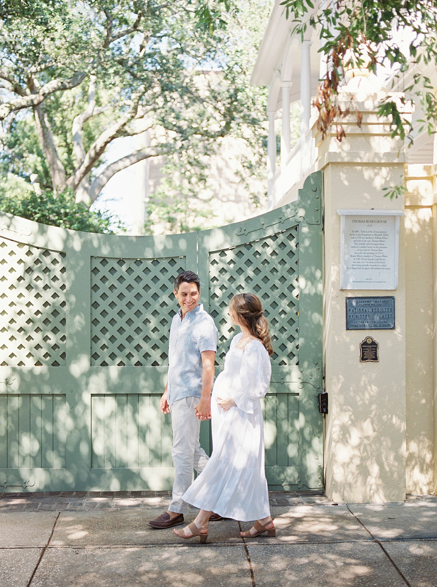 Mom and dad to be walking in front of a green gate | Photo by Caitlyn Motycka Photography