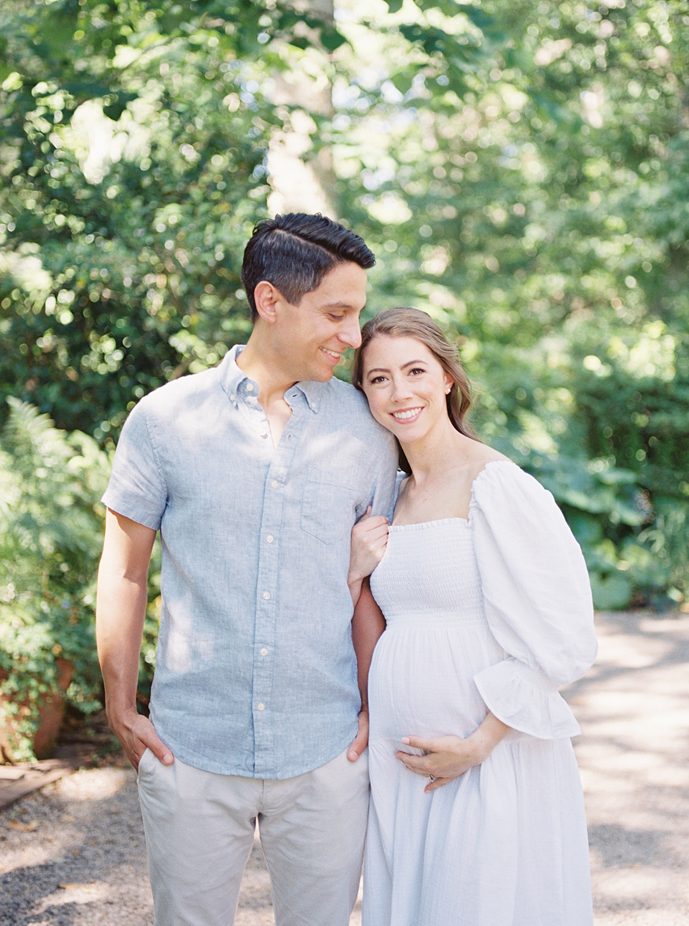 Mom and dad to be snuggling walking down the sidewalk | Photo by Caitlyn Motycka Photography