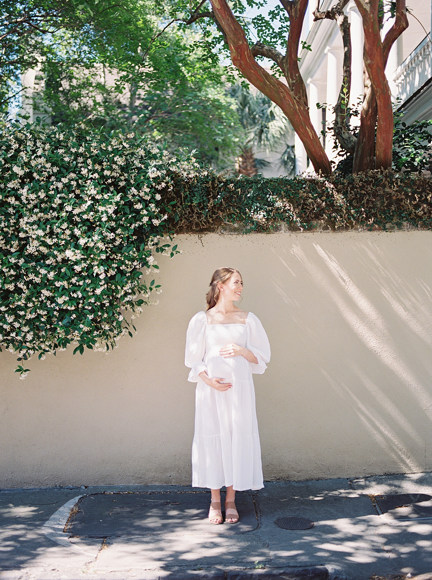Mother to be standing in front of cream covered wall | Photo by Charleston Film Photographer Caitlyn Motycka