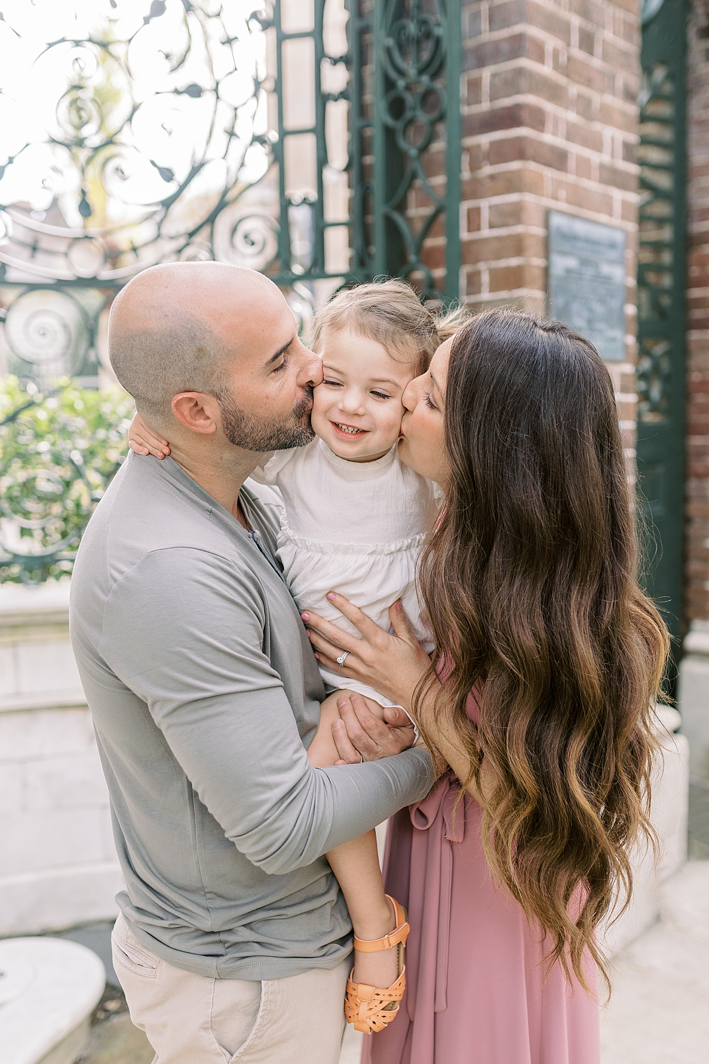 Mom and dad kissing their baby girl on the cheek | Photo by Caitlyn Motycka Photography