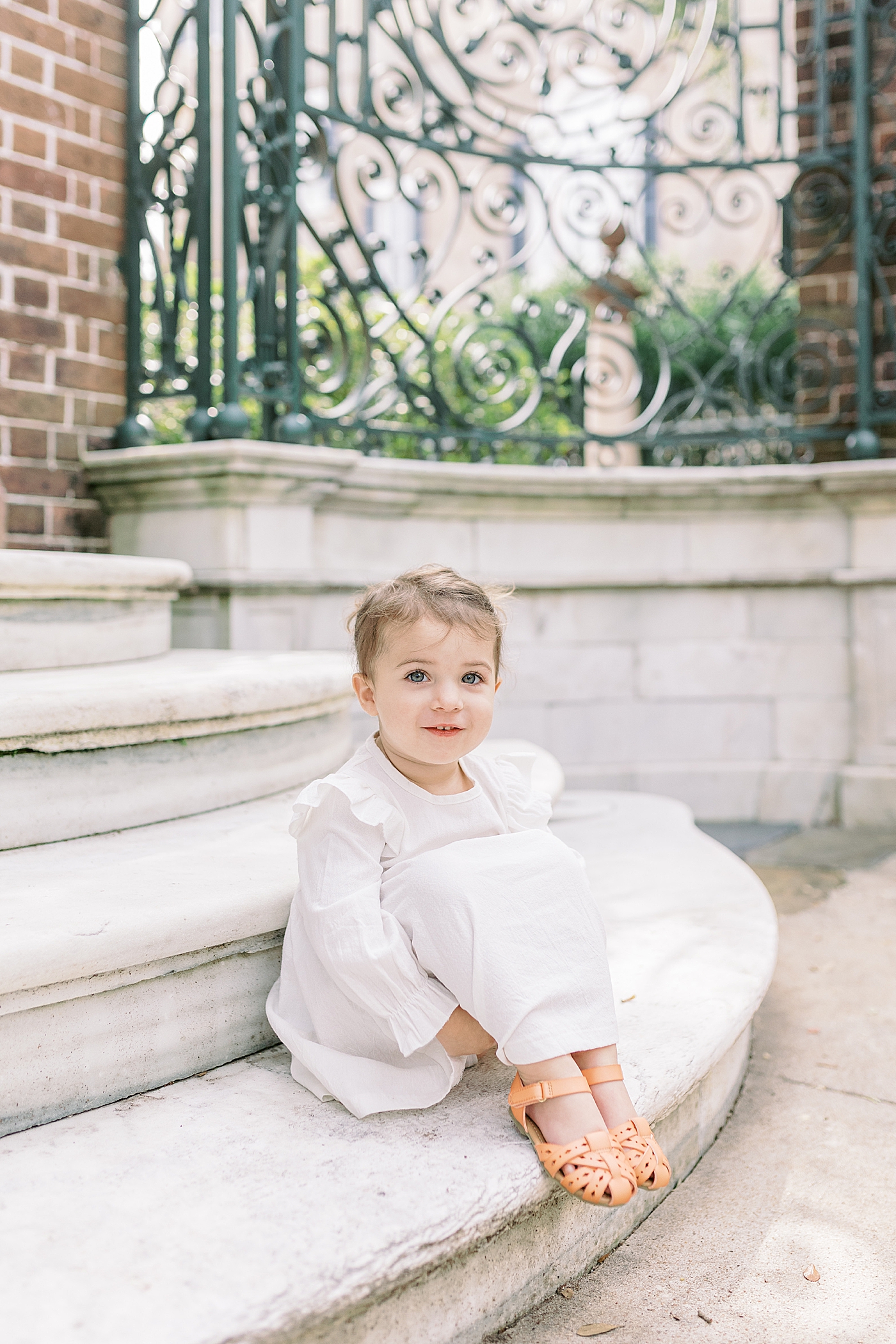 Toddler girl with pigtails and white dress sitting on a stoop during Fall Family Mini Session | Photo by Caitlyn Motycka Photography