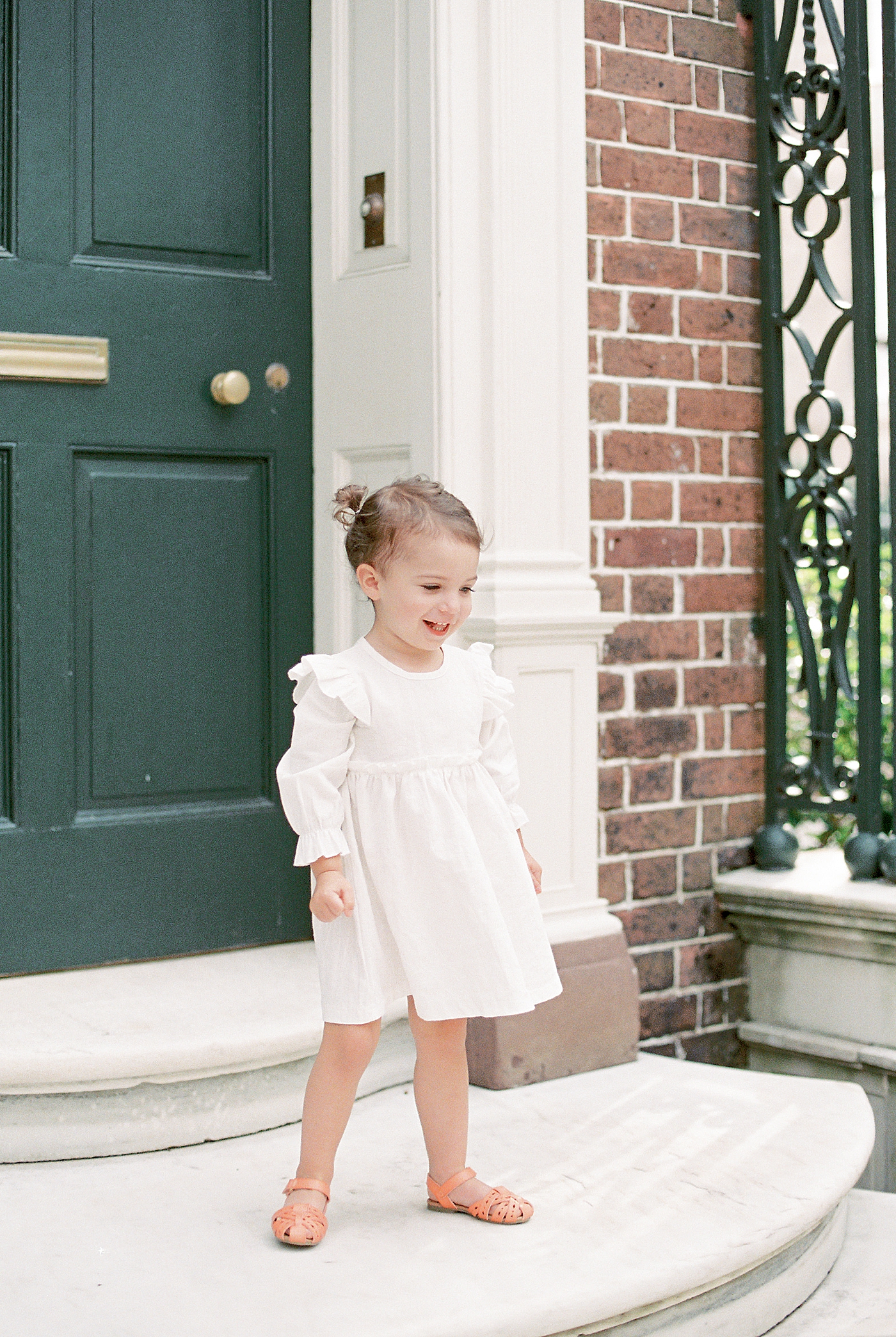 Little girl in white dress standing on a stoop | Photo by Caitlyn Motycka Photography