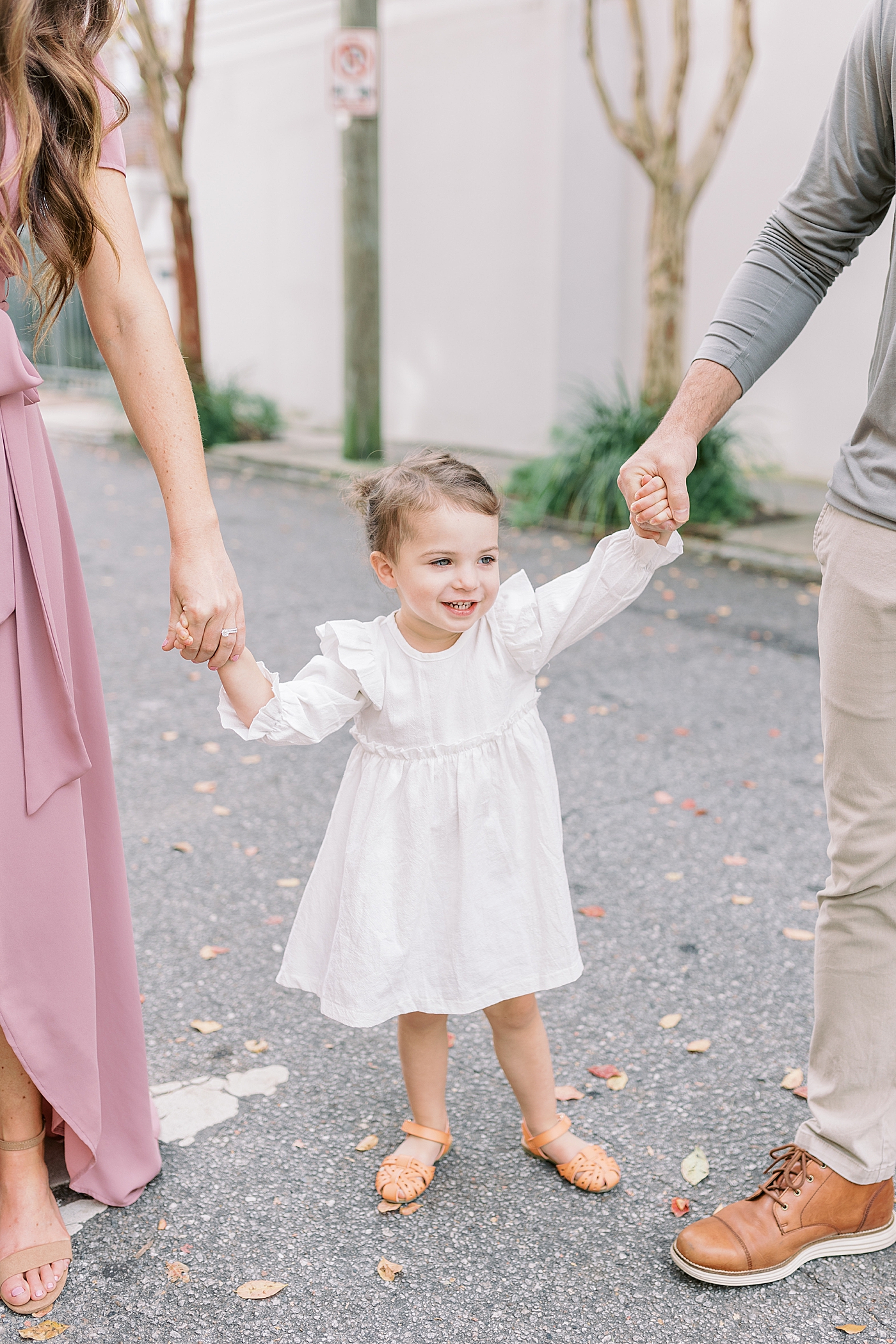 Little girl holding her mom and dad's hands during their Fall Family Mini Session | Photo by Caitlyn Motycka Photography