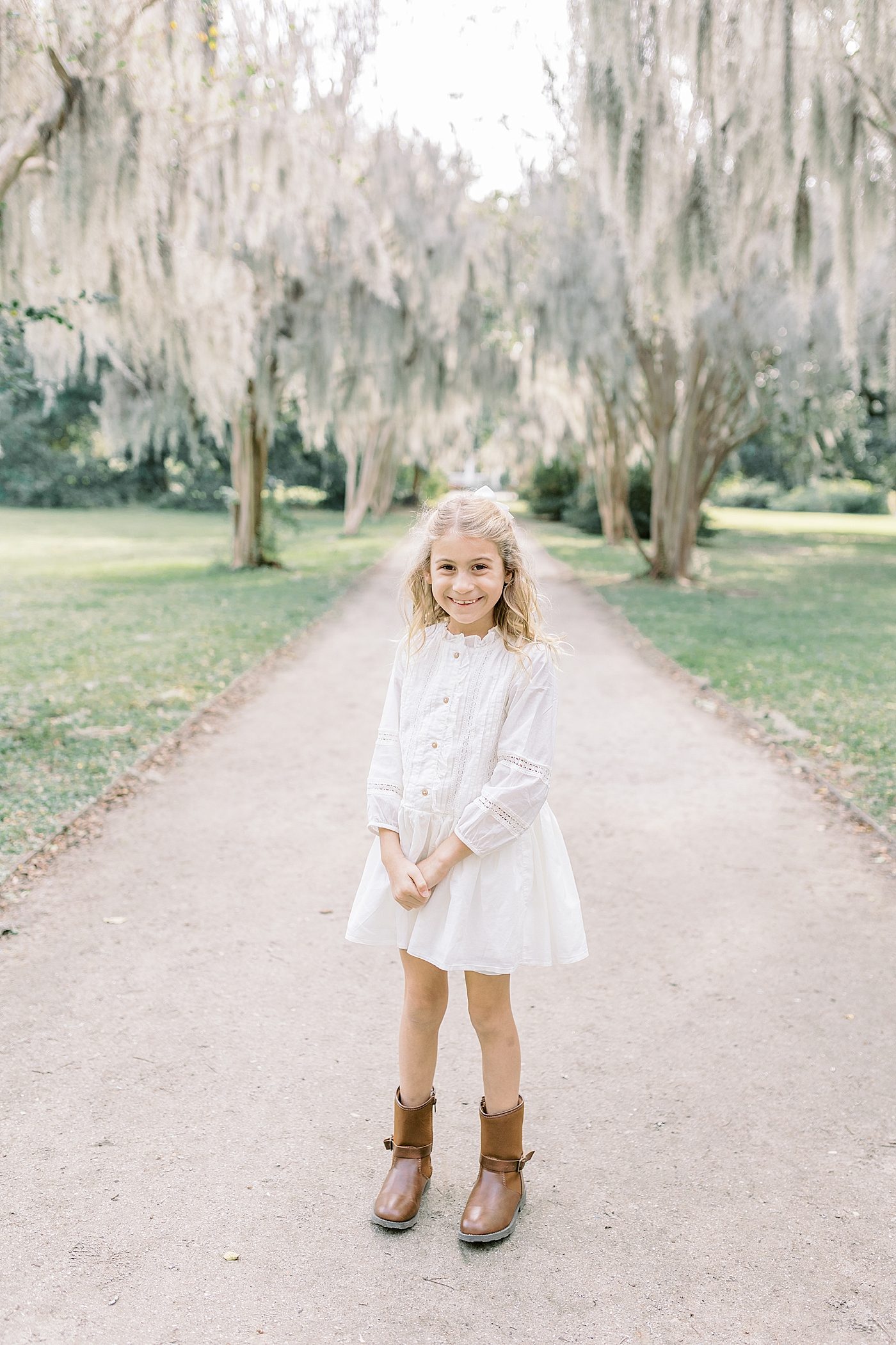 Little sister in white dress in the park during Fall Family Photos in Charleston | Photo by Caitlyn Motycka Photography