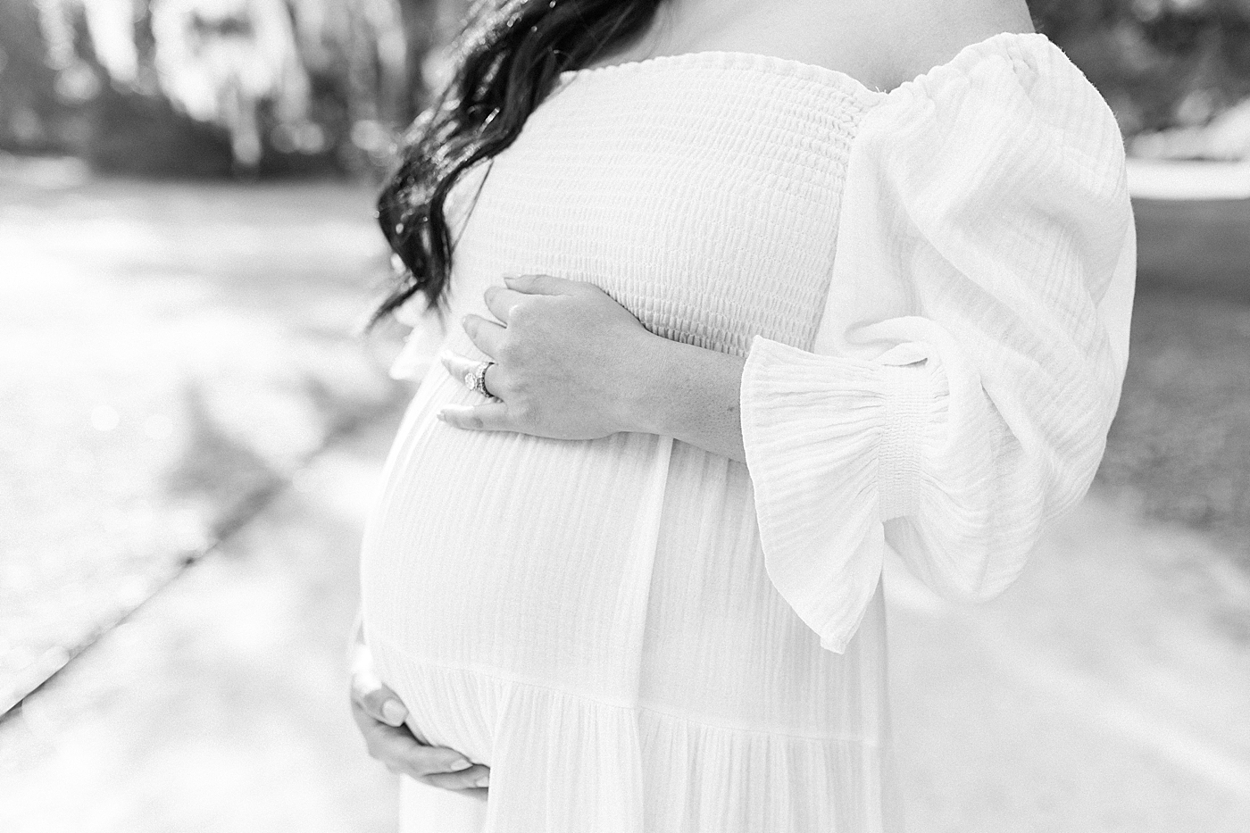 Black and white photo of mother to be holding her belly during her maternity photos in Charleston | Photo by Caitlyn Motycka Photography