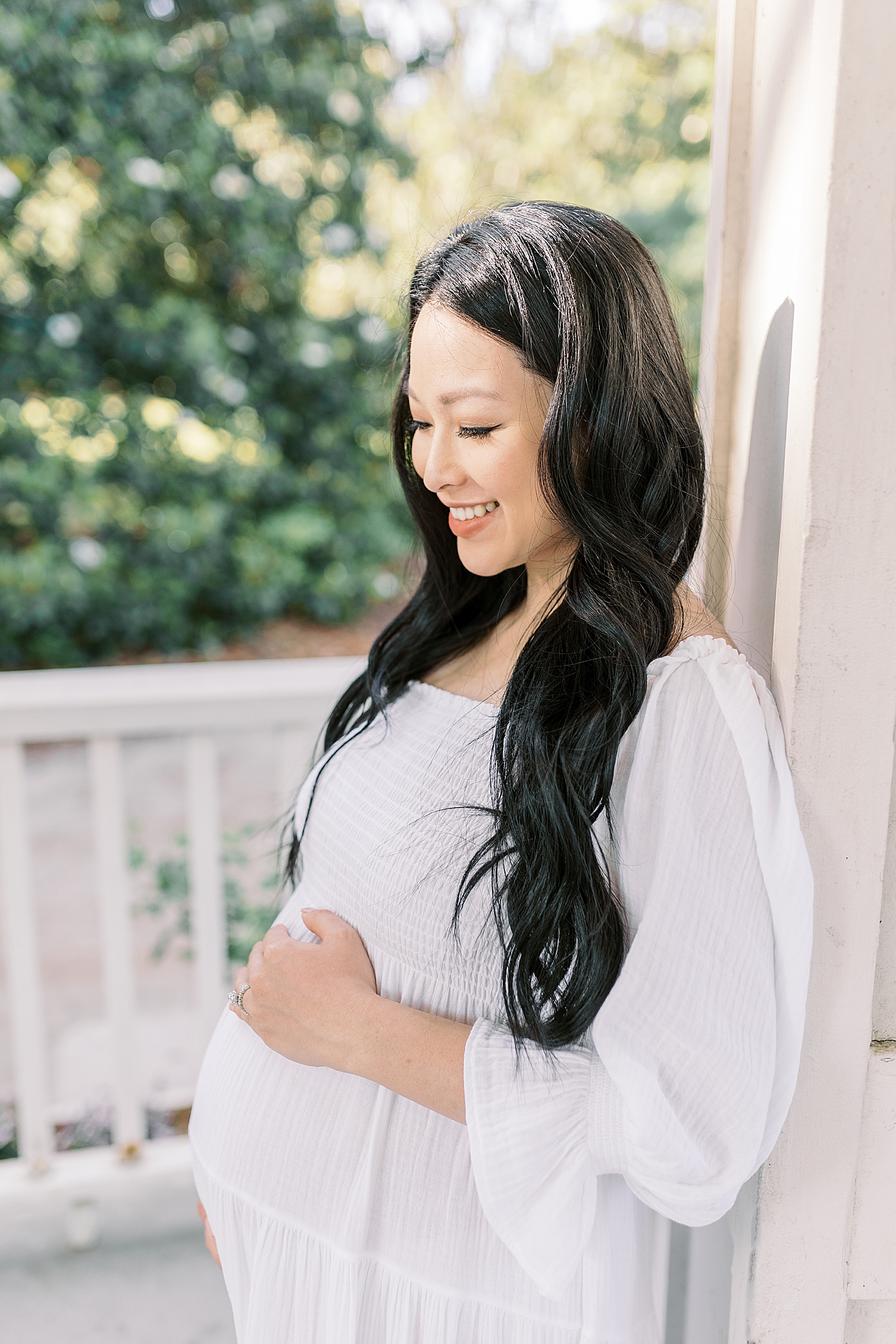 Smiling mother to be in a white dress | Photo by Caitlyn Motycka Photography