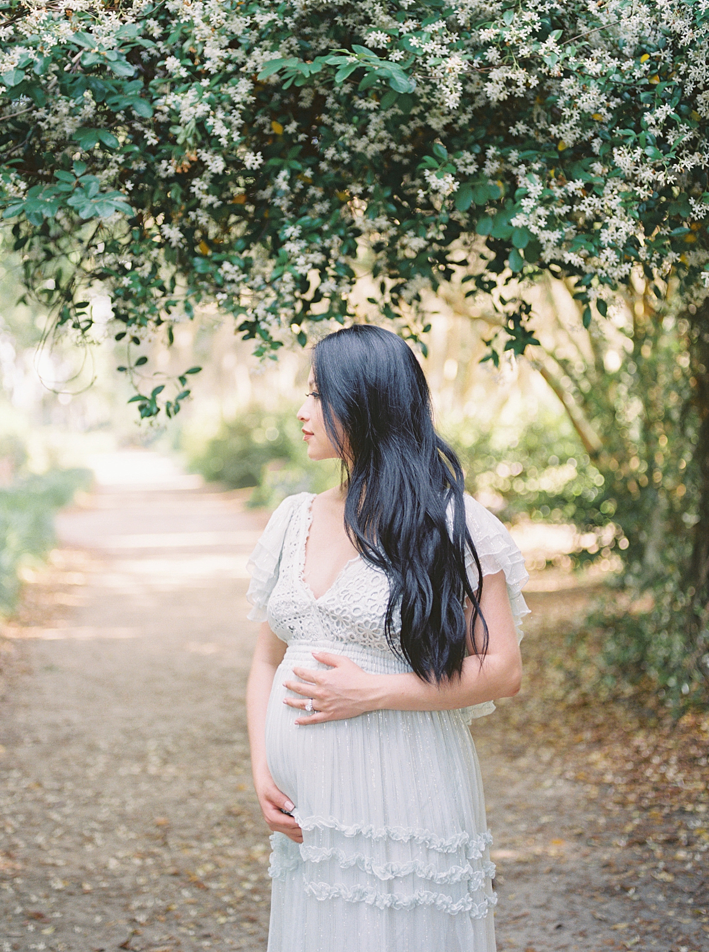 Mother to be with long dark hair holding her belly | Photo by Caitlyn Motycka Photography