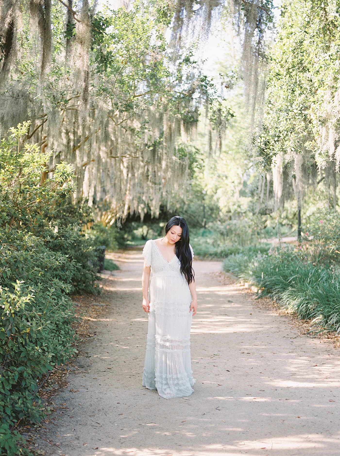 Mother to be walking down a path with spanish moss during maternity photos in Charleston | Photo by Caitlyn Motycka Photography