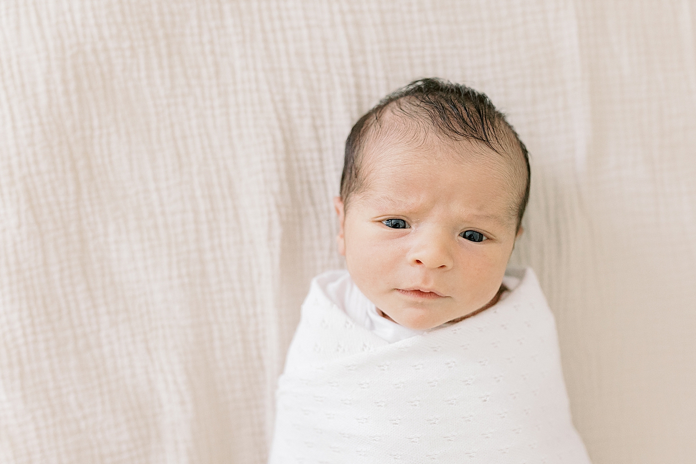 Newborn baby wrapped in a white swaddle | Photo by Caitlyn Motycka Photography