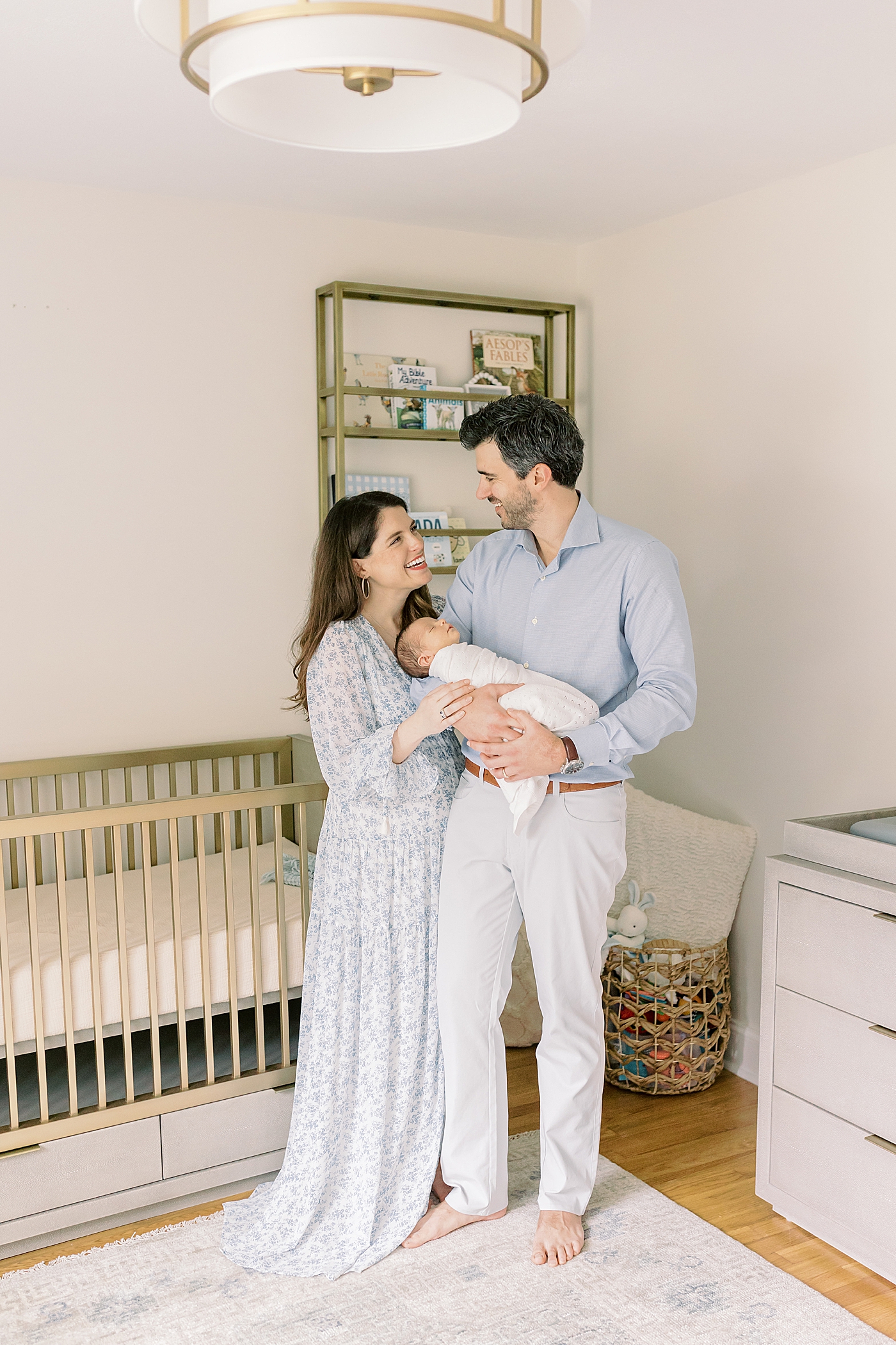 Mom and dad smiling holding their new baby in the nursery | Photo by Mount Pleasant Newborn Photographer Caitlyn Motycka