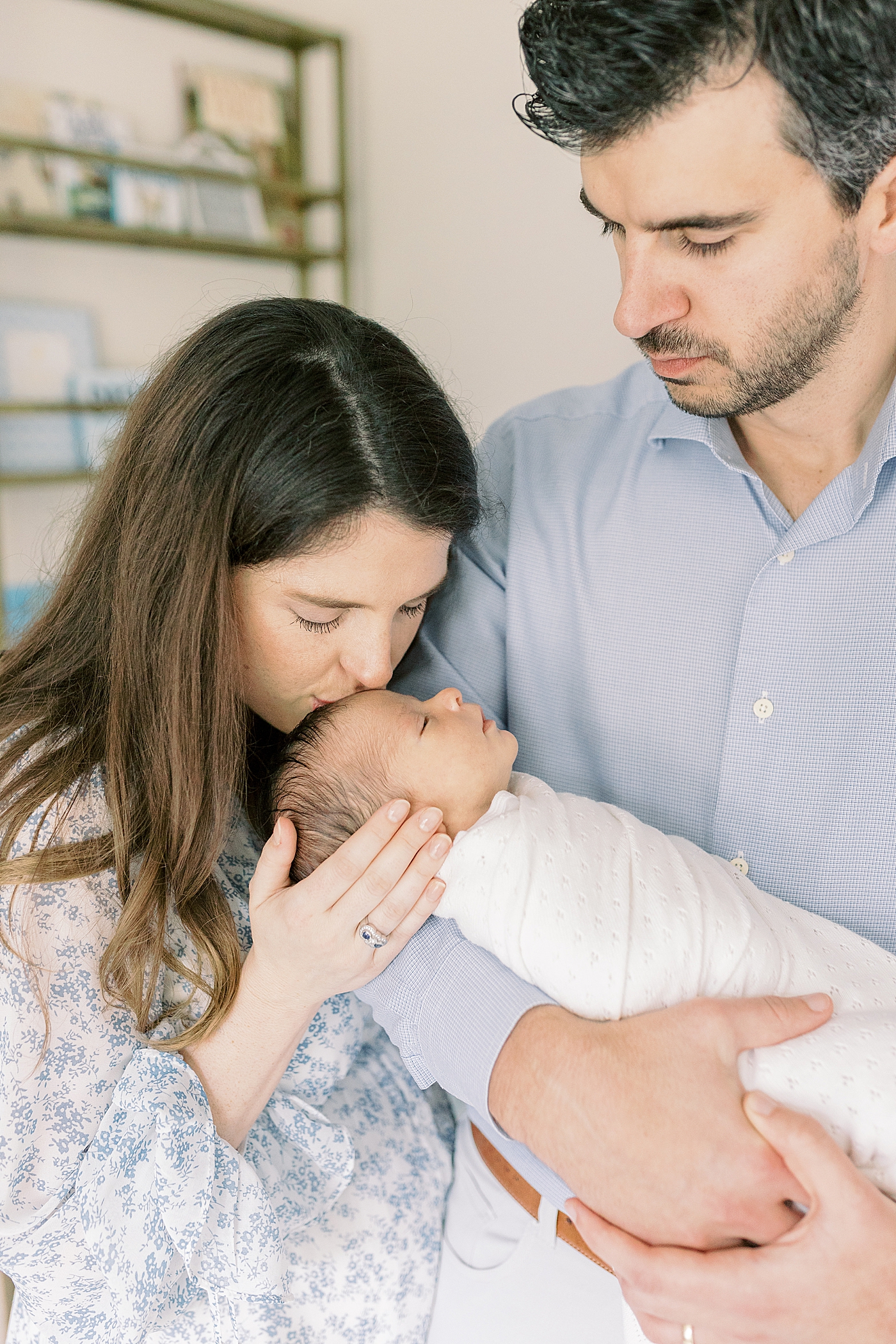 Dad holding newborn while mom kisses him on the head | Photo by Mount Pleasant Newborn Photographer Caitlyn Motycka