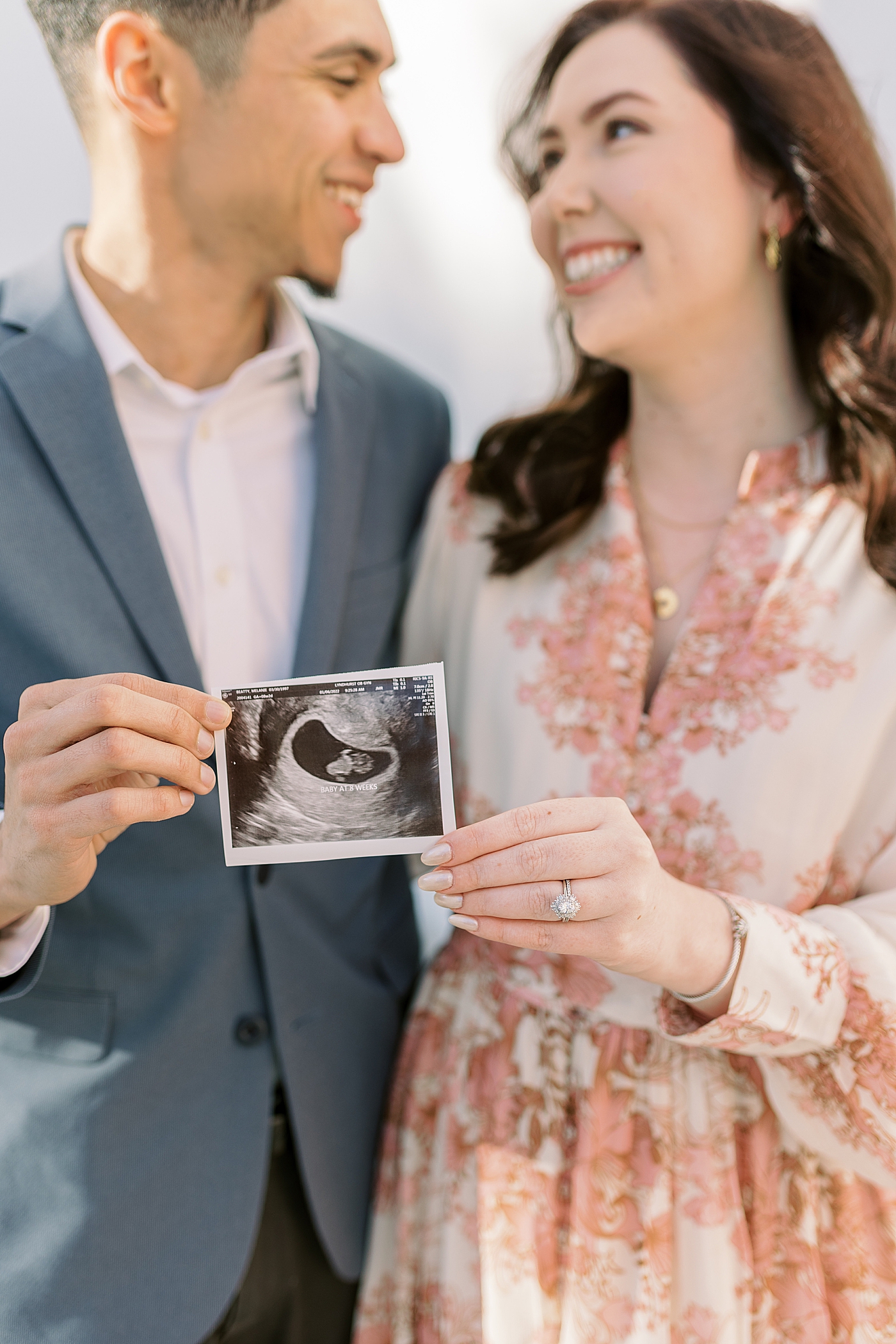 Mom and dad to be holding their sonogram photo and smiling | Photo by Caitlyn Motycka Photography