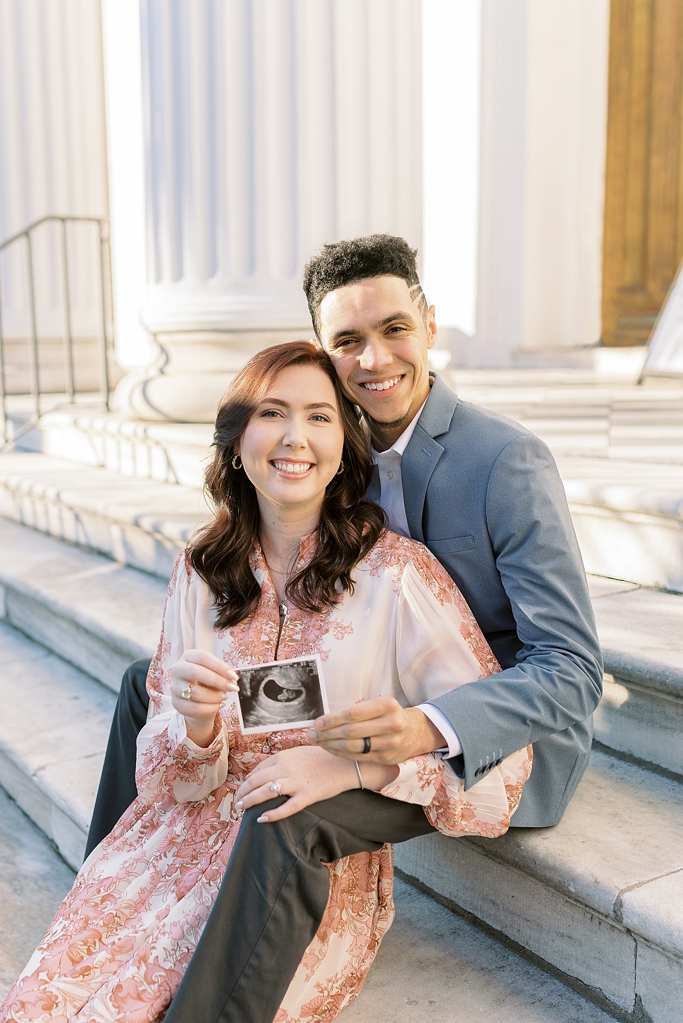 Mom and dad to be smiling holding their sonogram image | Photo by Caitlyn Motycka Photography