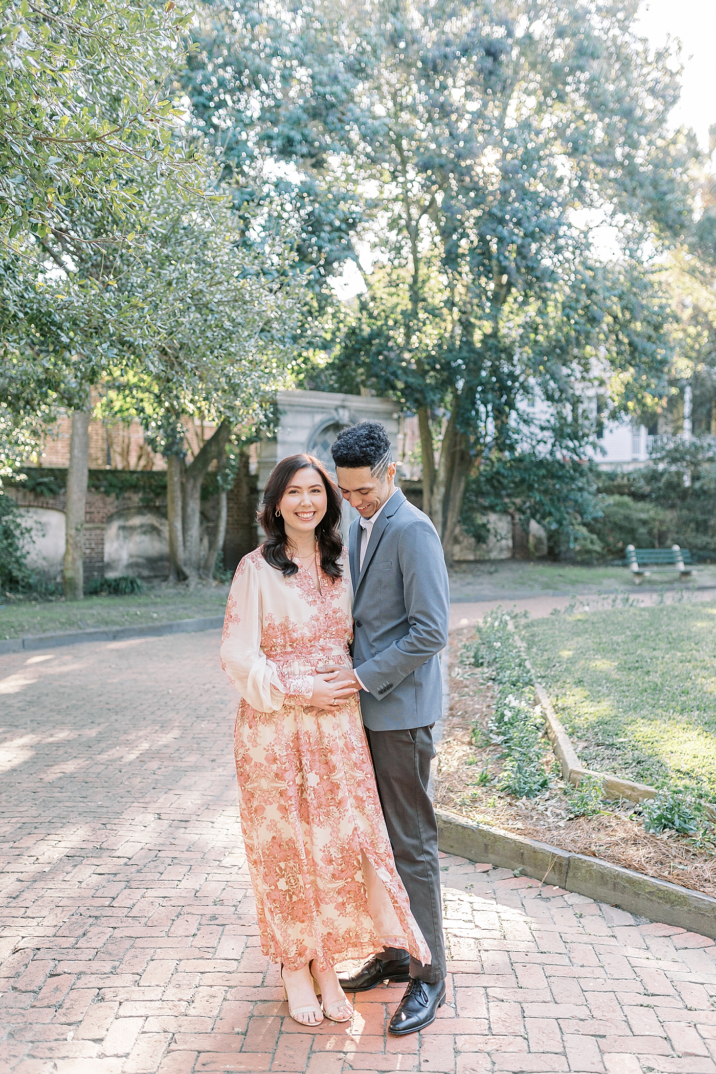 Mother and father to be snuggling a park during their Pregnancy Announcement in Downtown Charleston | Photo by Caitlyn Motycka Photography