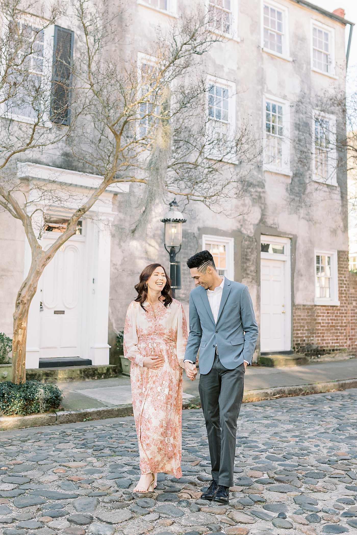 Couple laughing while walking down a cobblestone street in Charleston | Photo by Caitlyn Motycka Photography