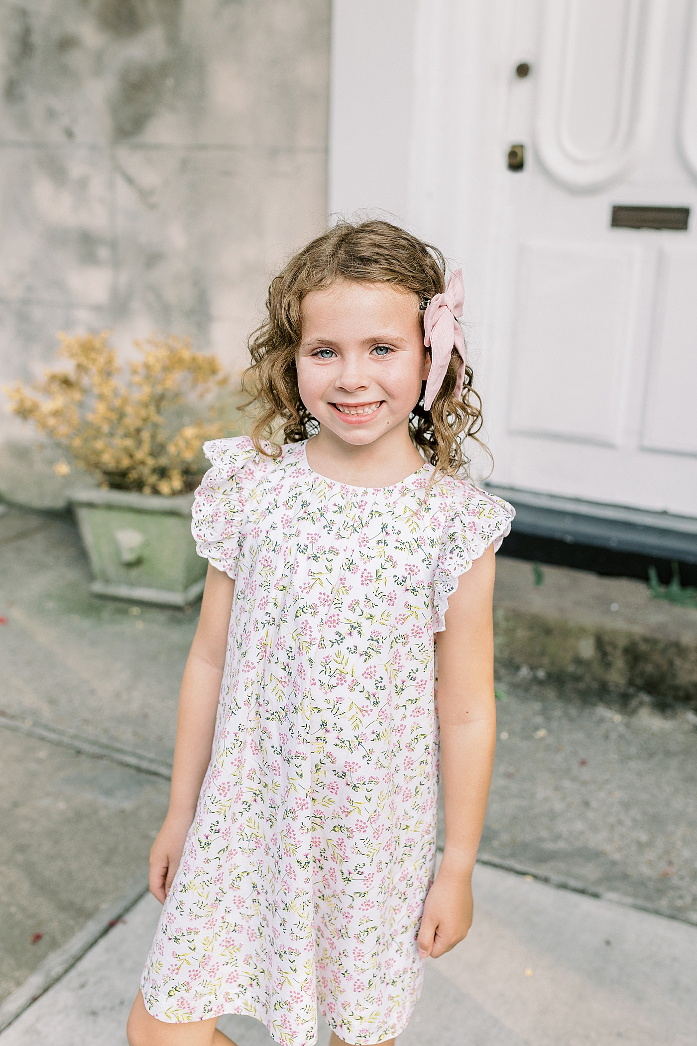 Little girl with a pink bow in a floral print dress | Photo by Caitlyn Motycka Photography