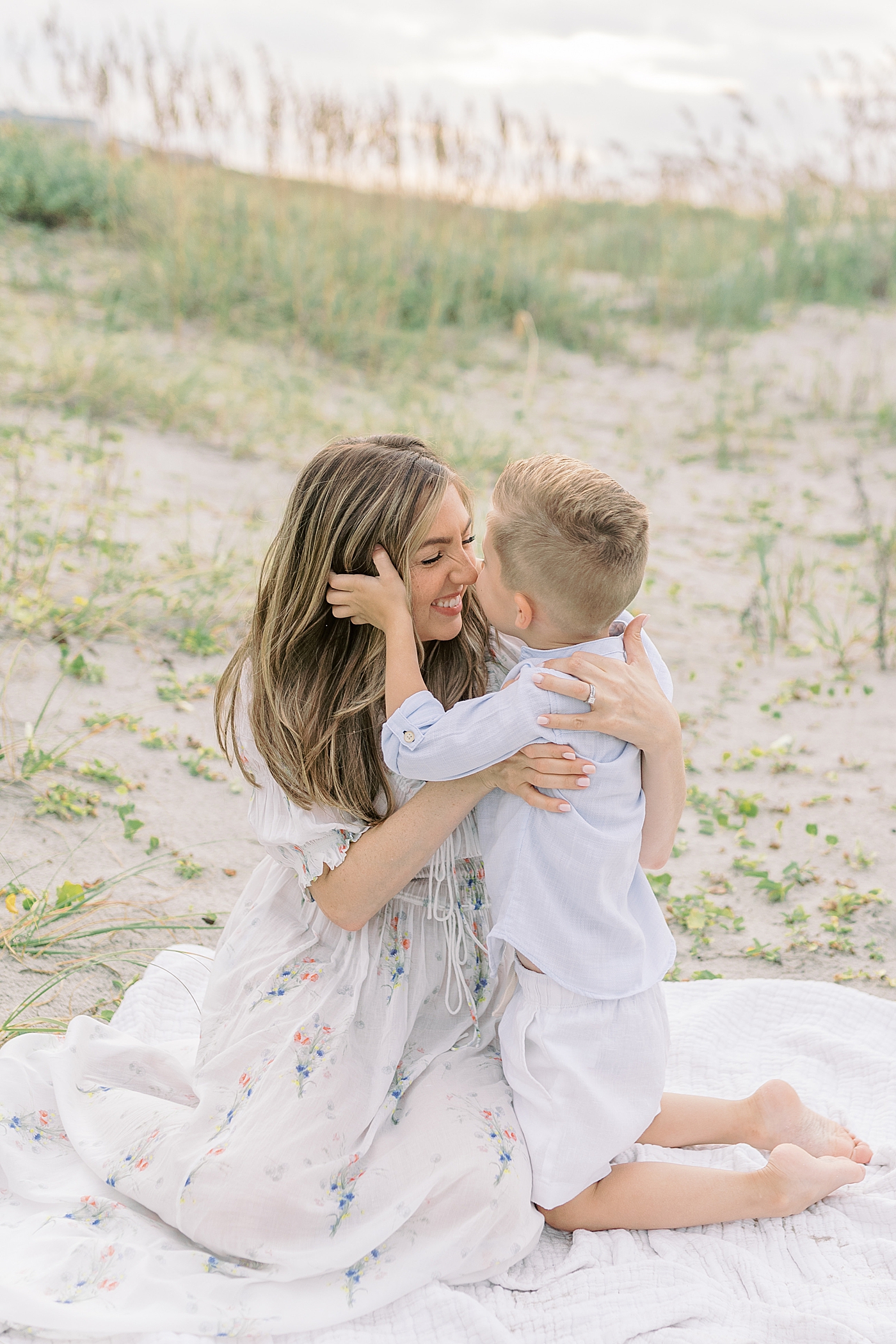 Mom snuggling with her little boy on the beach | Image by Caitlyn Motycka