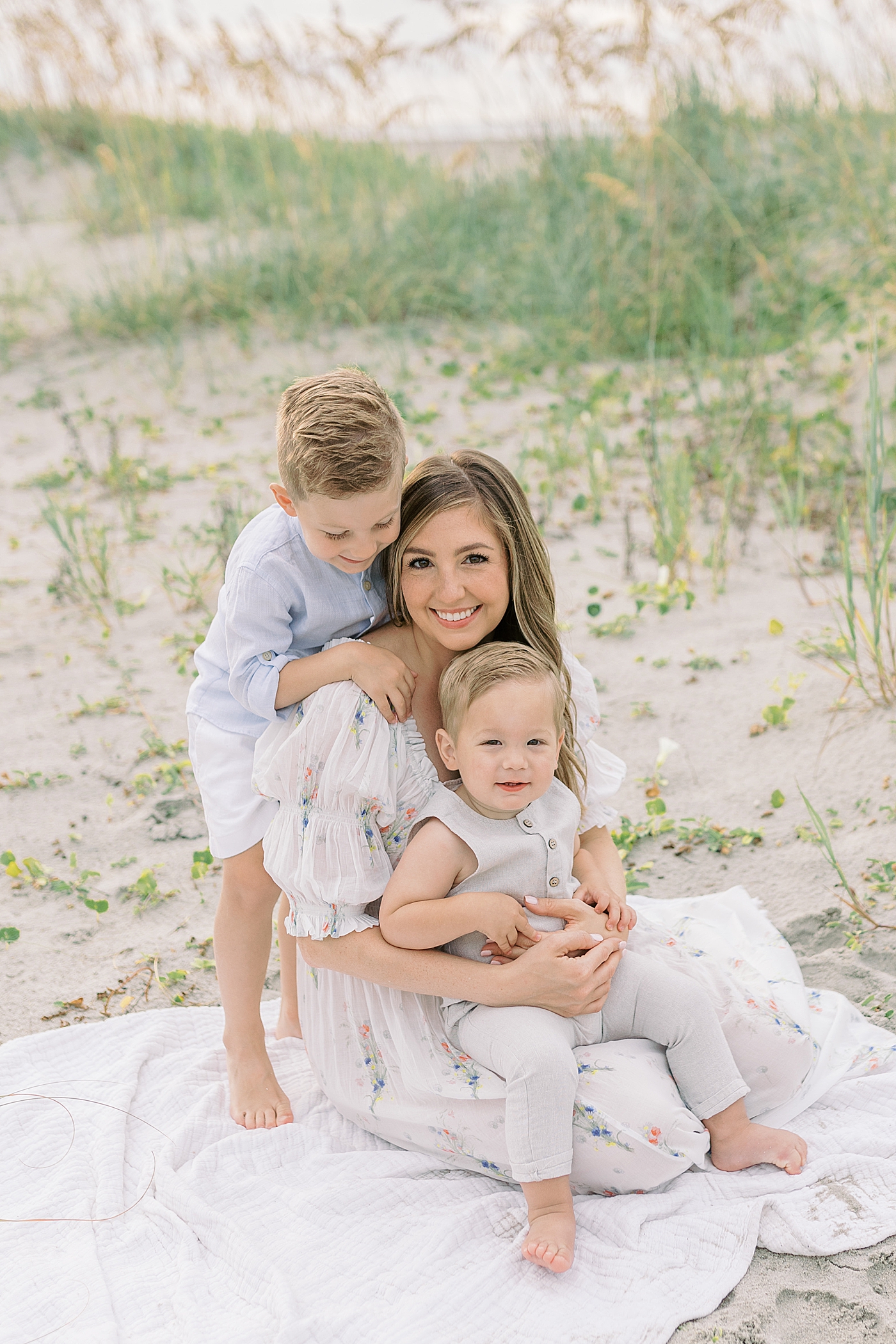 Mom with her two little boys on the beach | Image by Caitlyn Motycka