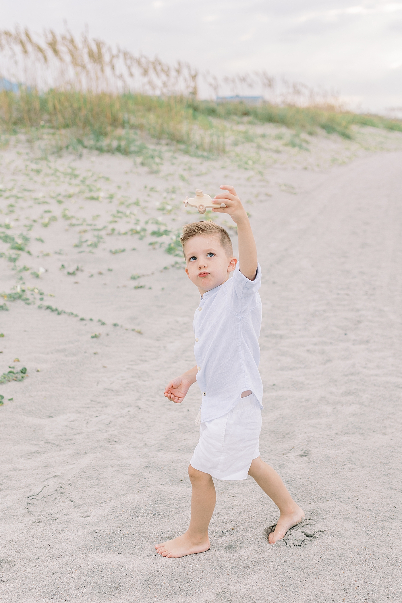 Little boy playing with a wooden airplane on the beach | Image by Caitlyn Motycka