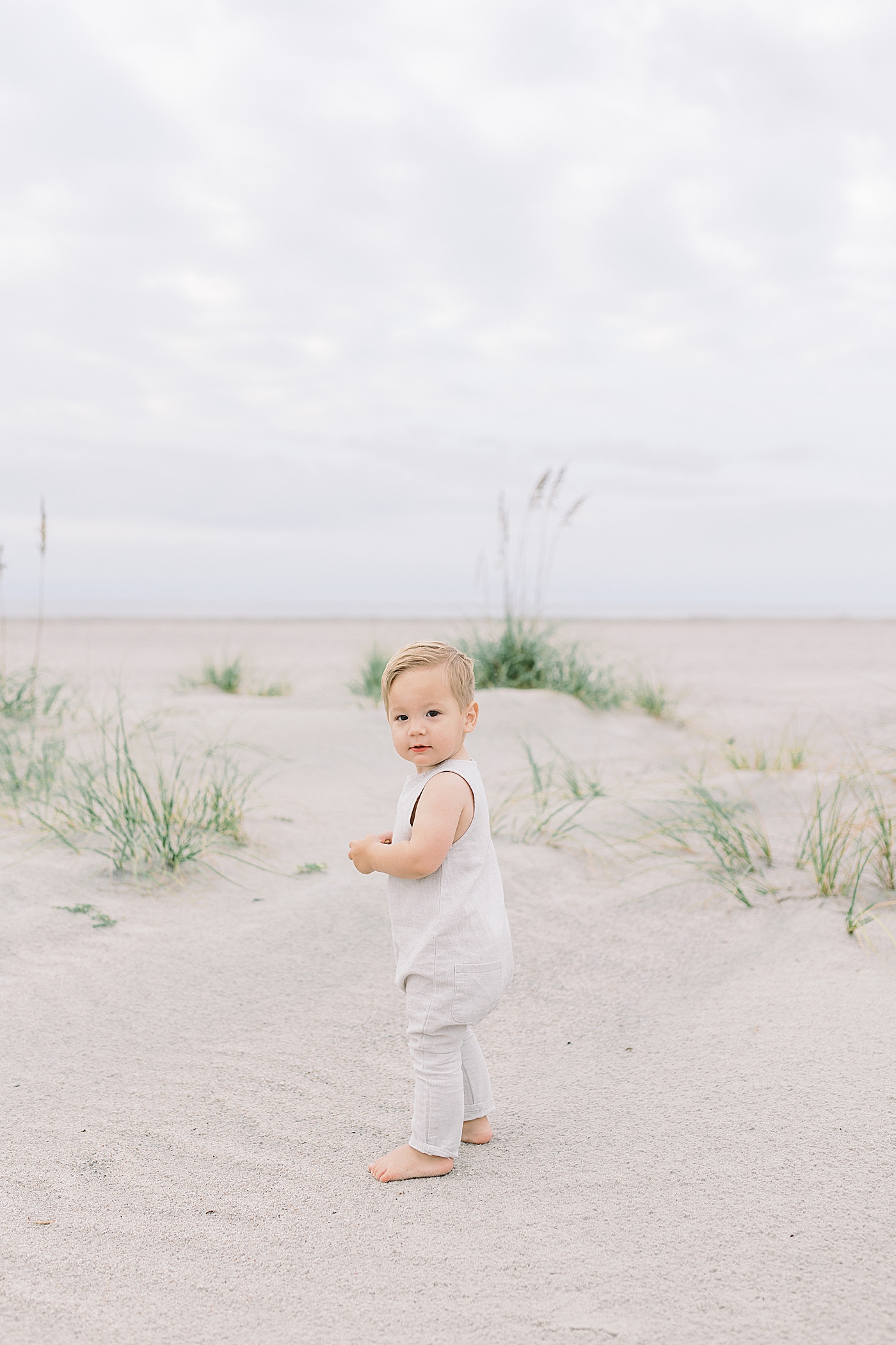 Baby in a jumper walking on the beach | Image by Caitlyn Motycka