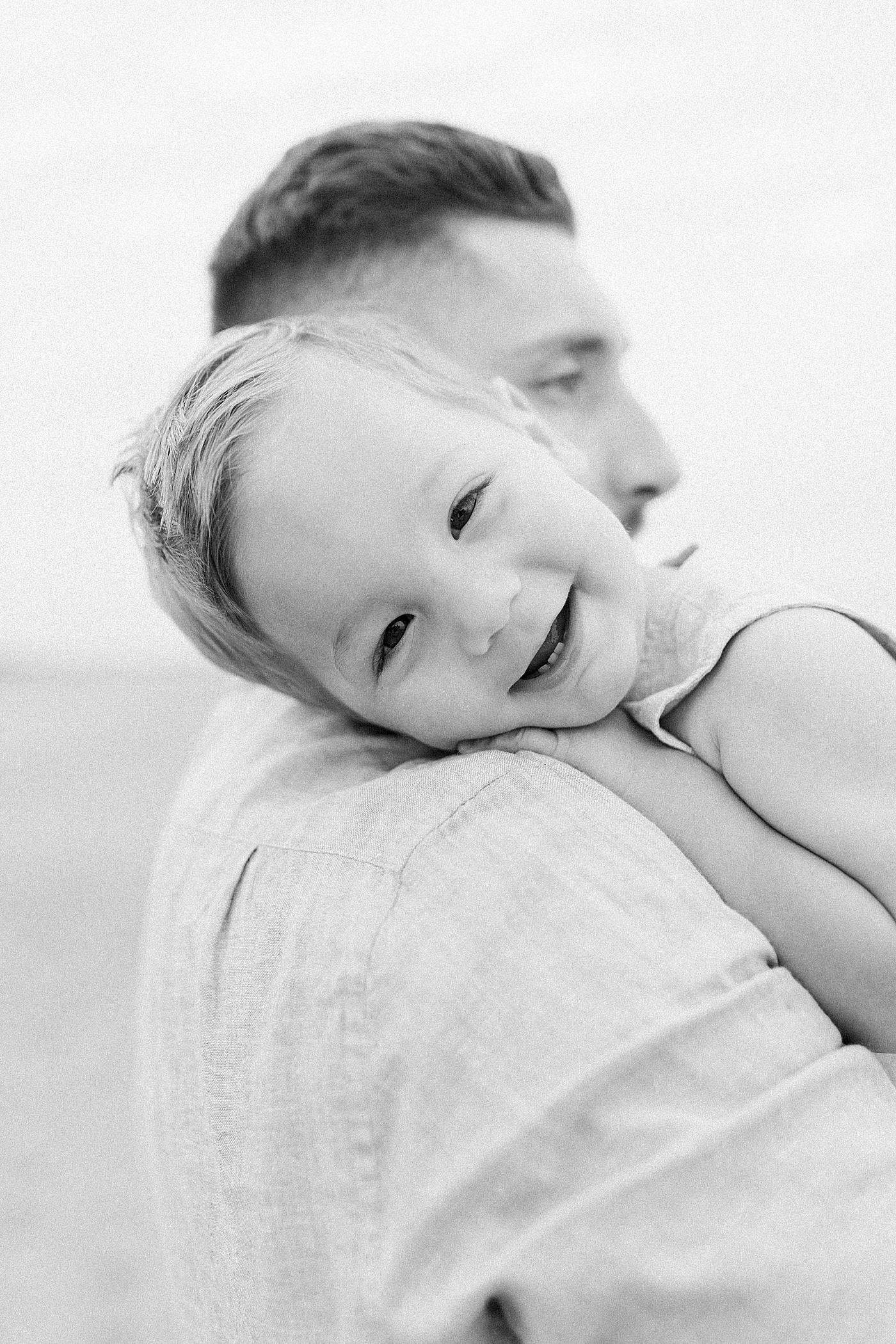 Black and white image of baby boy with his head on dads shoulder | Preparing for Family Beach Session with Caitlyn Motycka