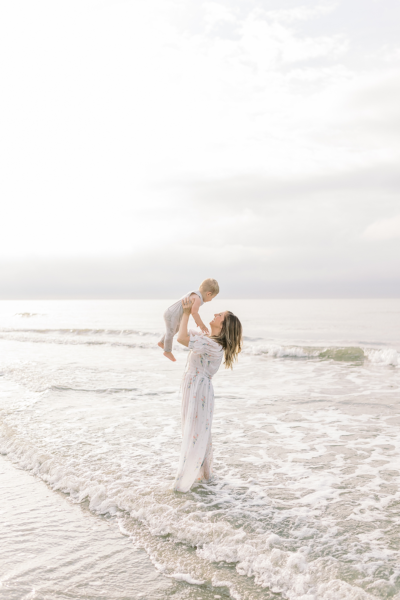 Mom standing in the ocean holding her baby boy | Preparing for Family Beach Session with Caitlyn Motycka