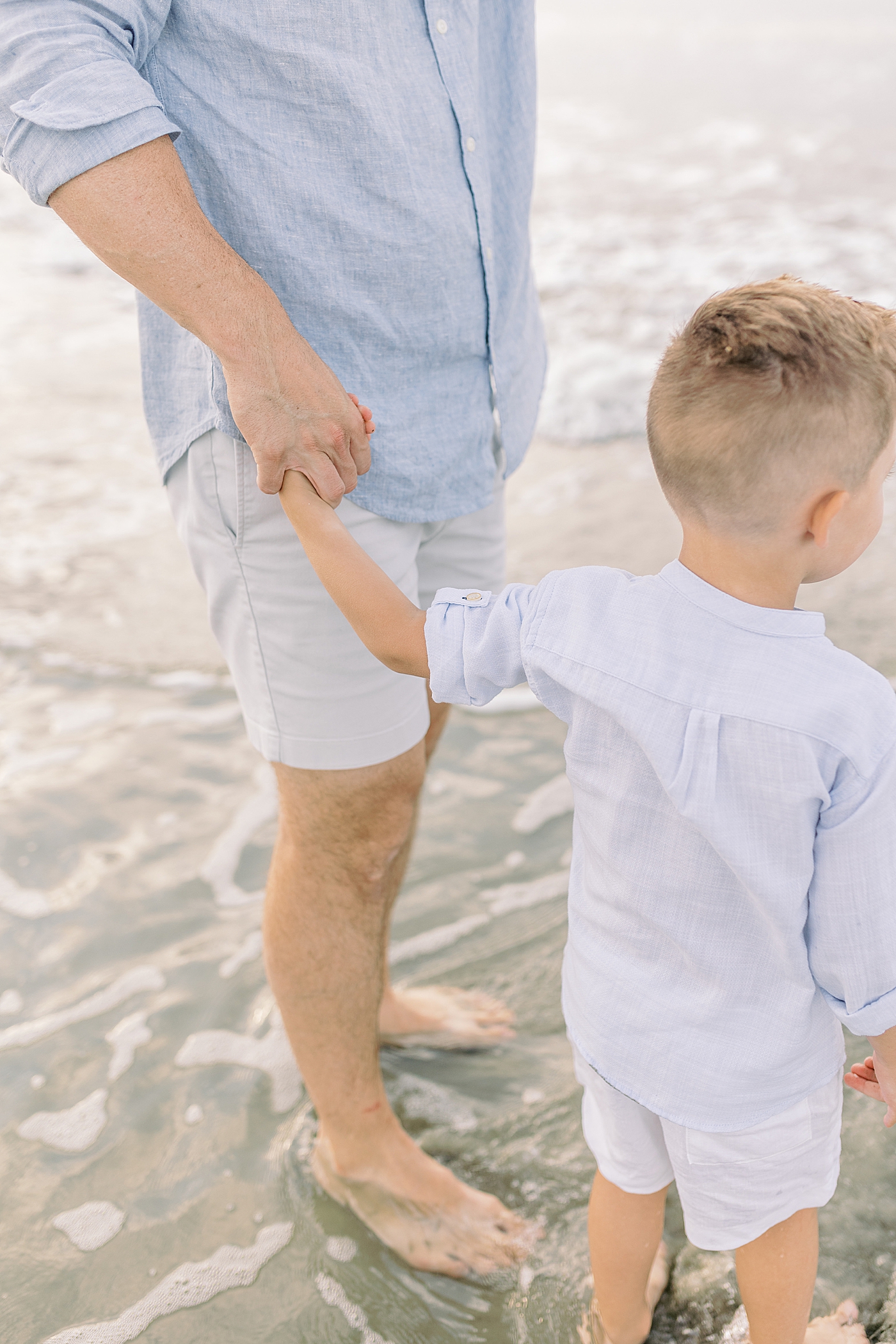 Dad holding his little boy's hand at the beach | Preparing for Family Beach Session with Caitlyn Motycka