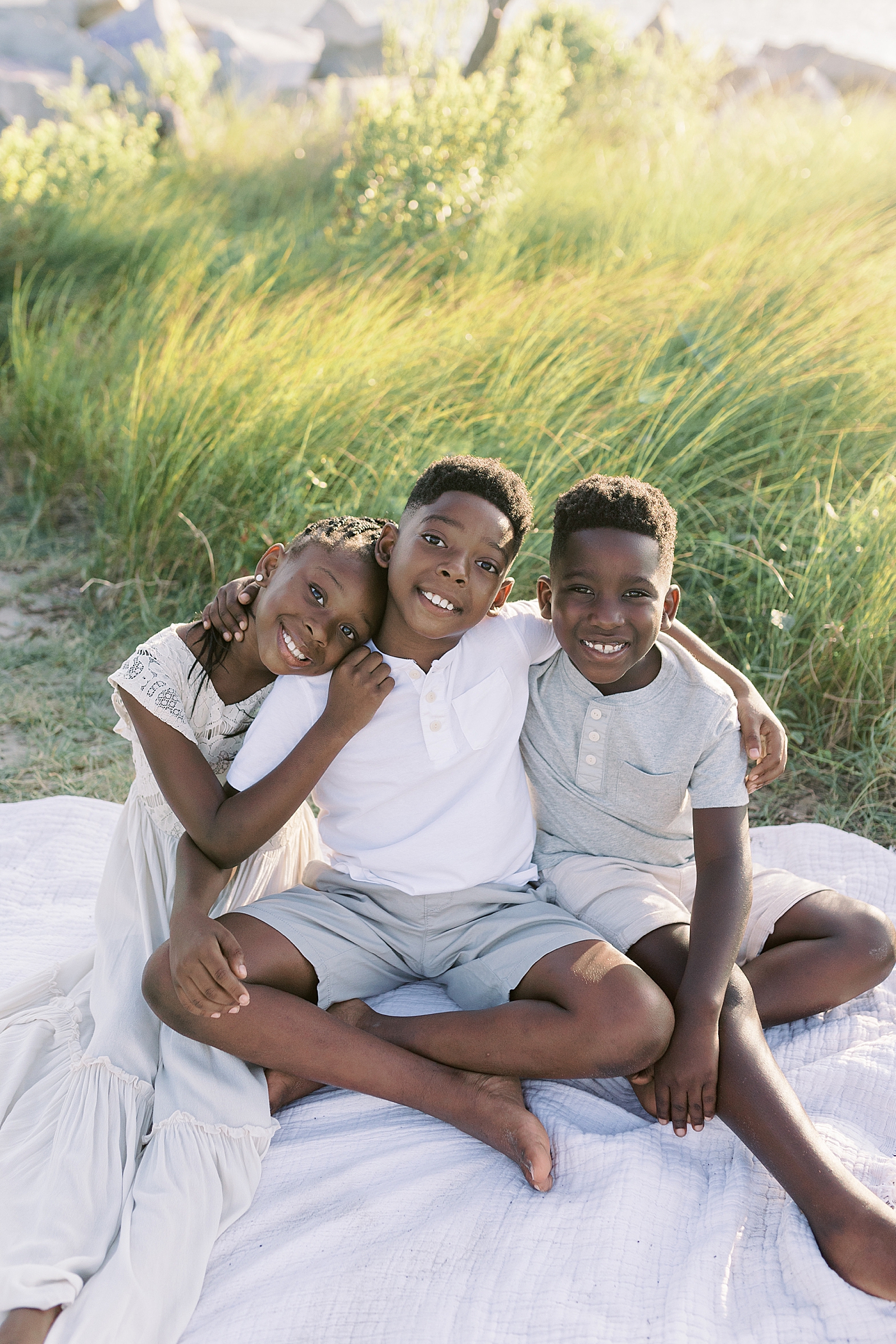 Sibling sitting on a picnic blanket during beach family photos in Charleston | Image by Caitlyn Motycka