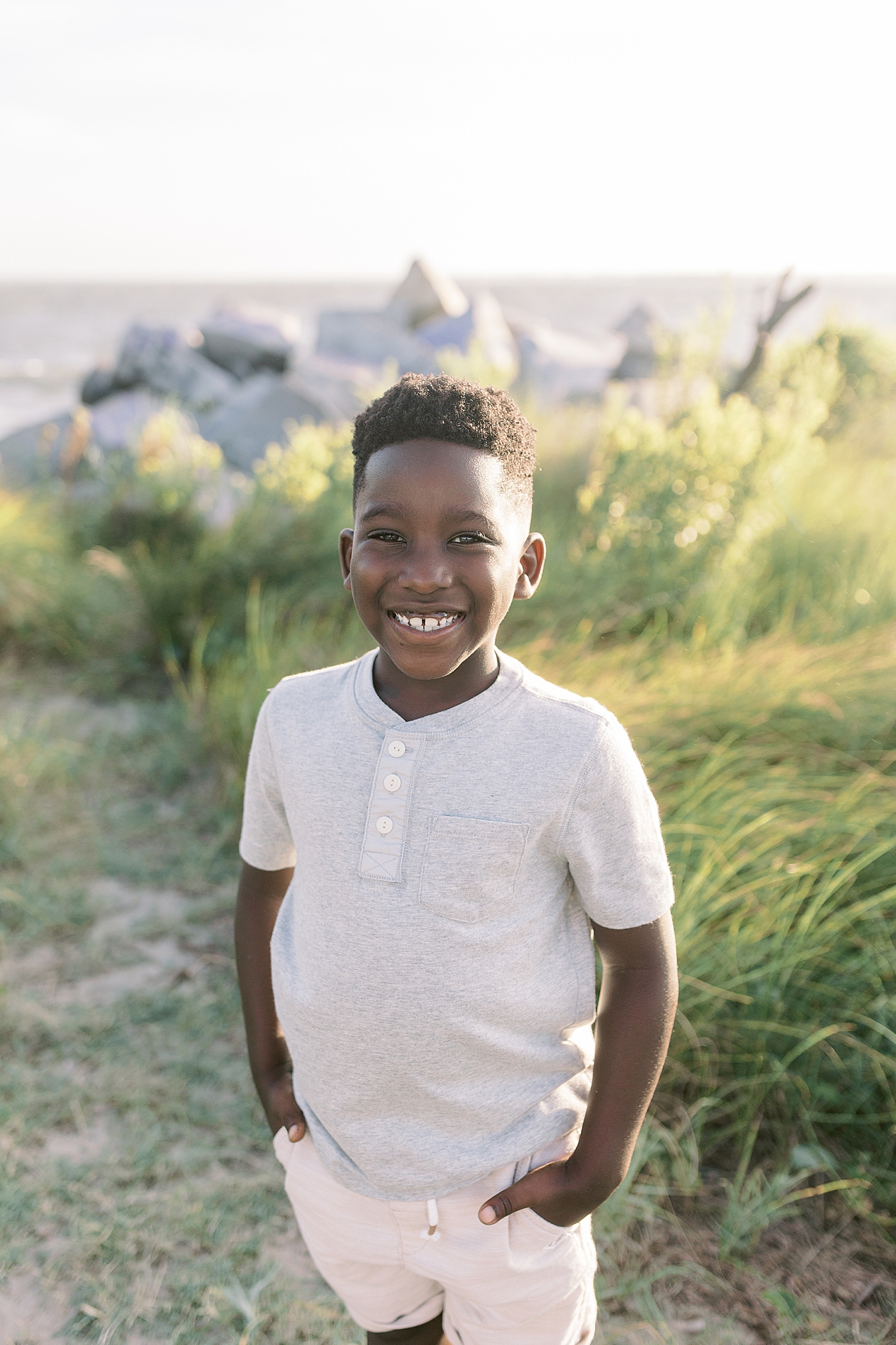 Little boy with hands in his pockets during beach family photos in Charleston | Image by Caitlyn Motycka