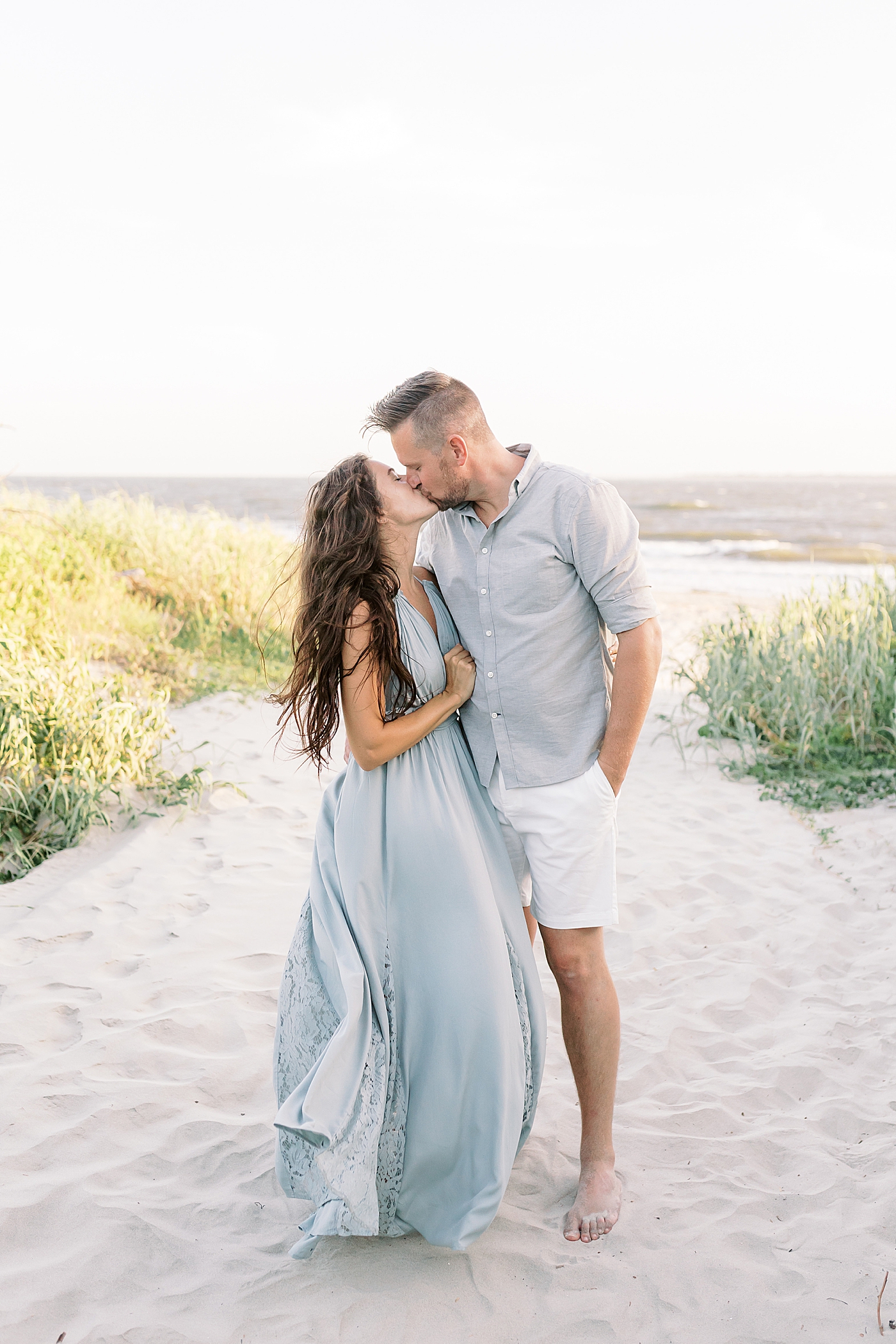 Mom and dad kiss during beach family photos in Charleston | Image by Caitlyn Motycka