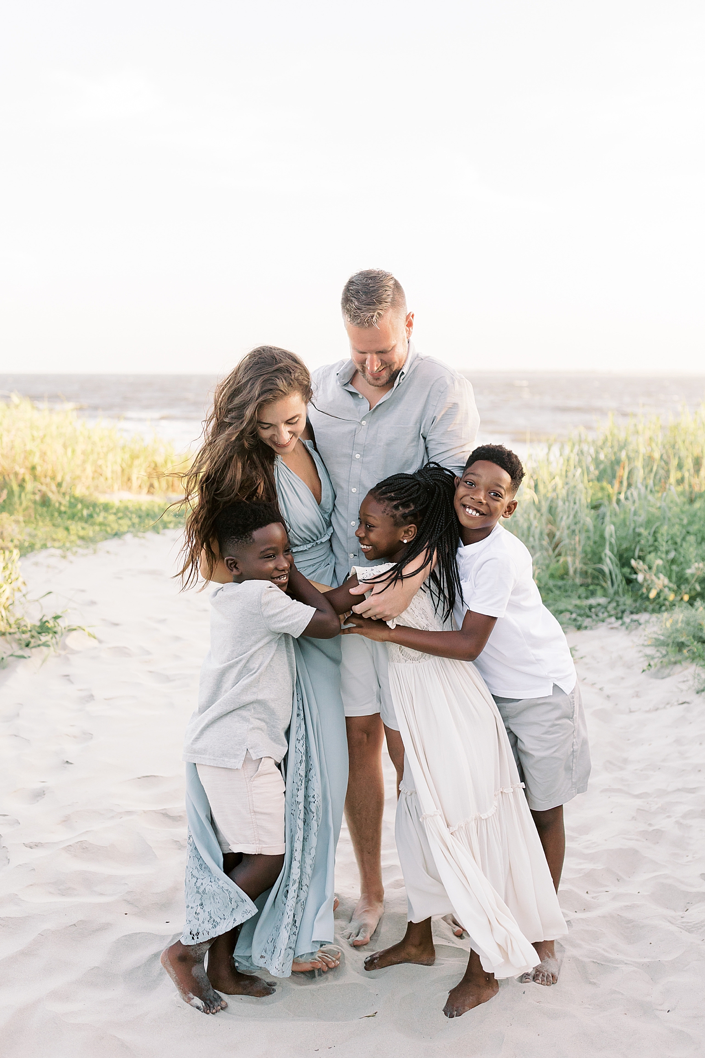 Family snuggling during beach family photos in Charleston | Image by Caitlyn Motycka