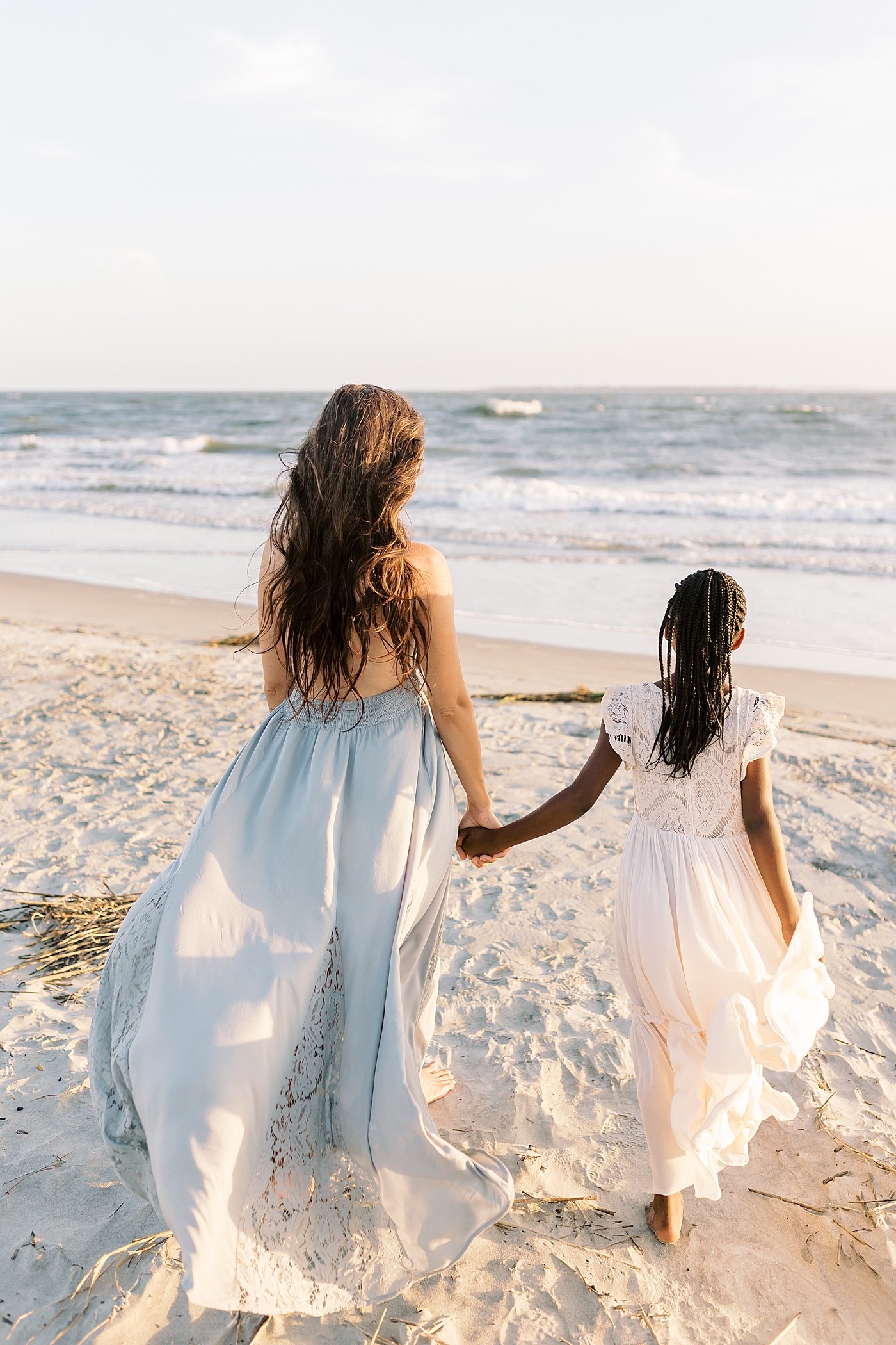 Mom and daughter walking on the beach | Image by Caitlyn Motycka