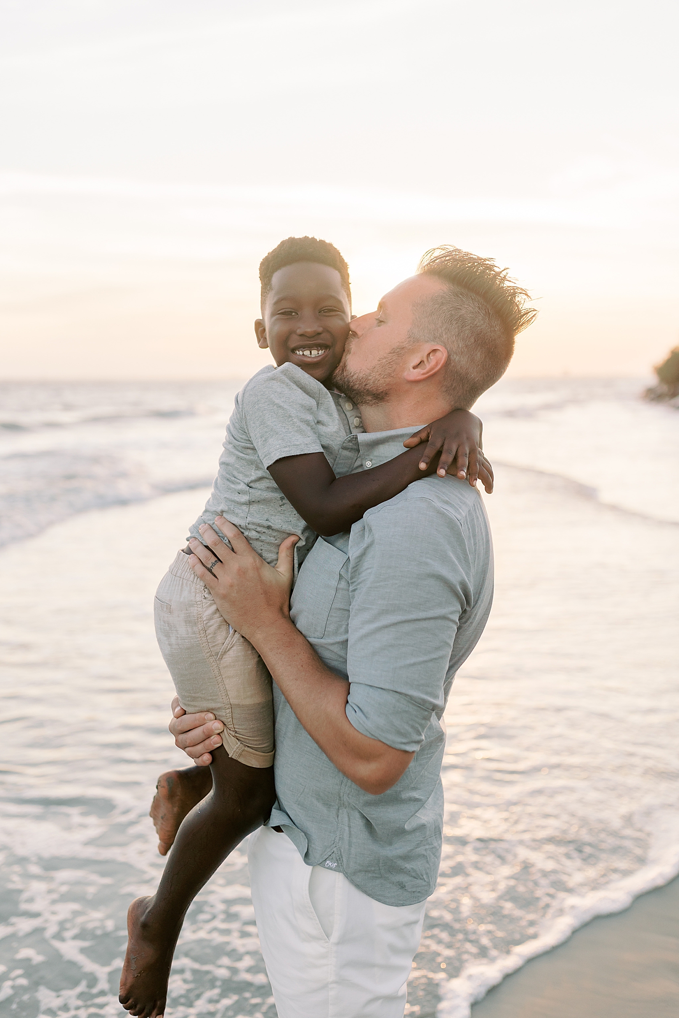 Dad holding his son during beach family photos in Charleston | Image by Caitlyn Motycka
