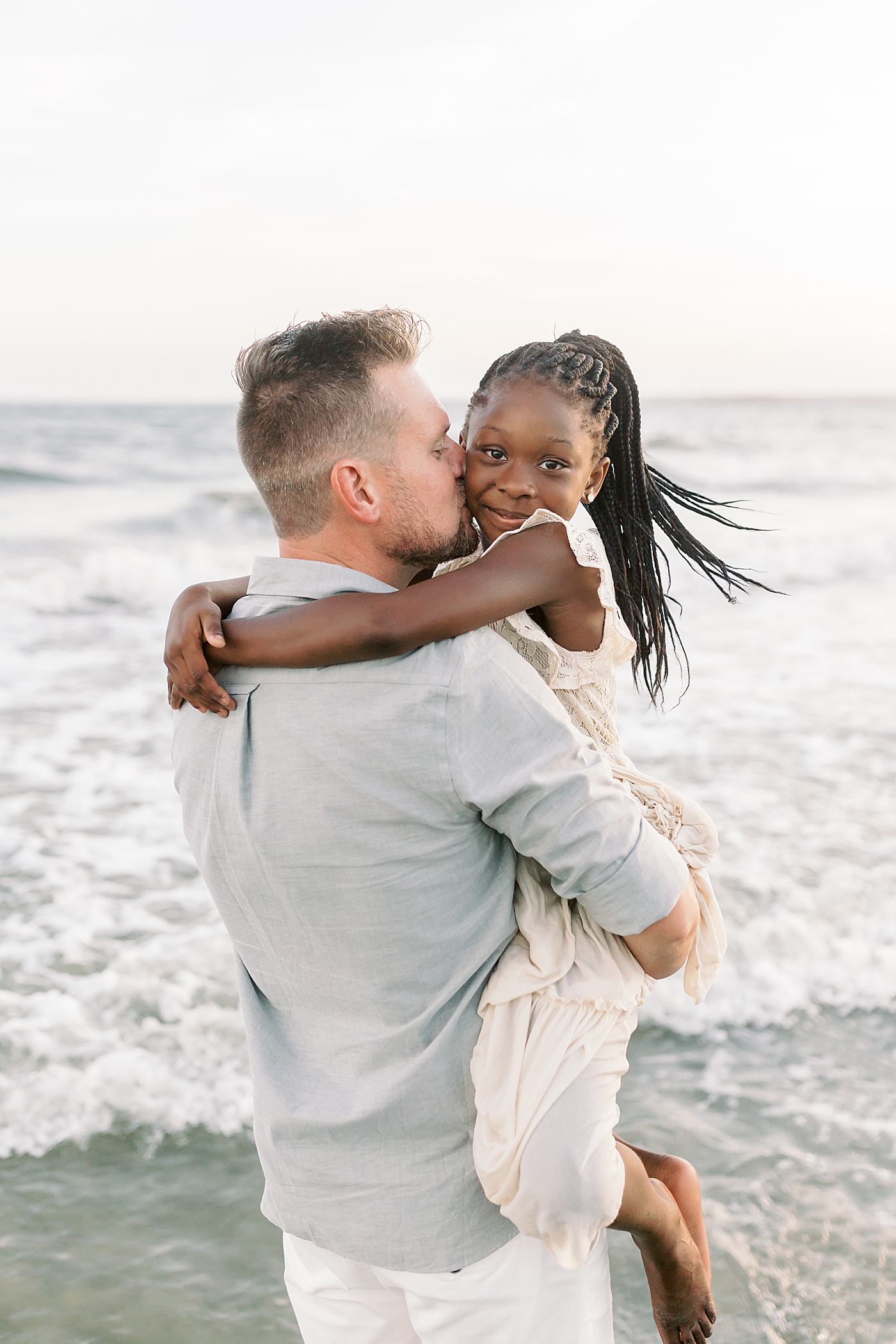 Dad snuggling with his daughter during beach family photos in Charleston | Image by Caitlyn Motycka