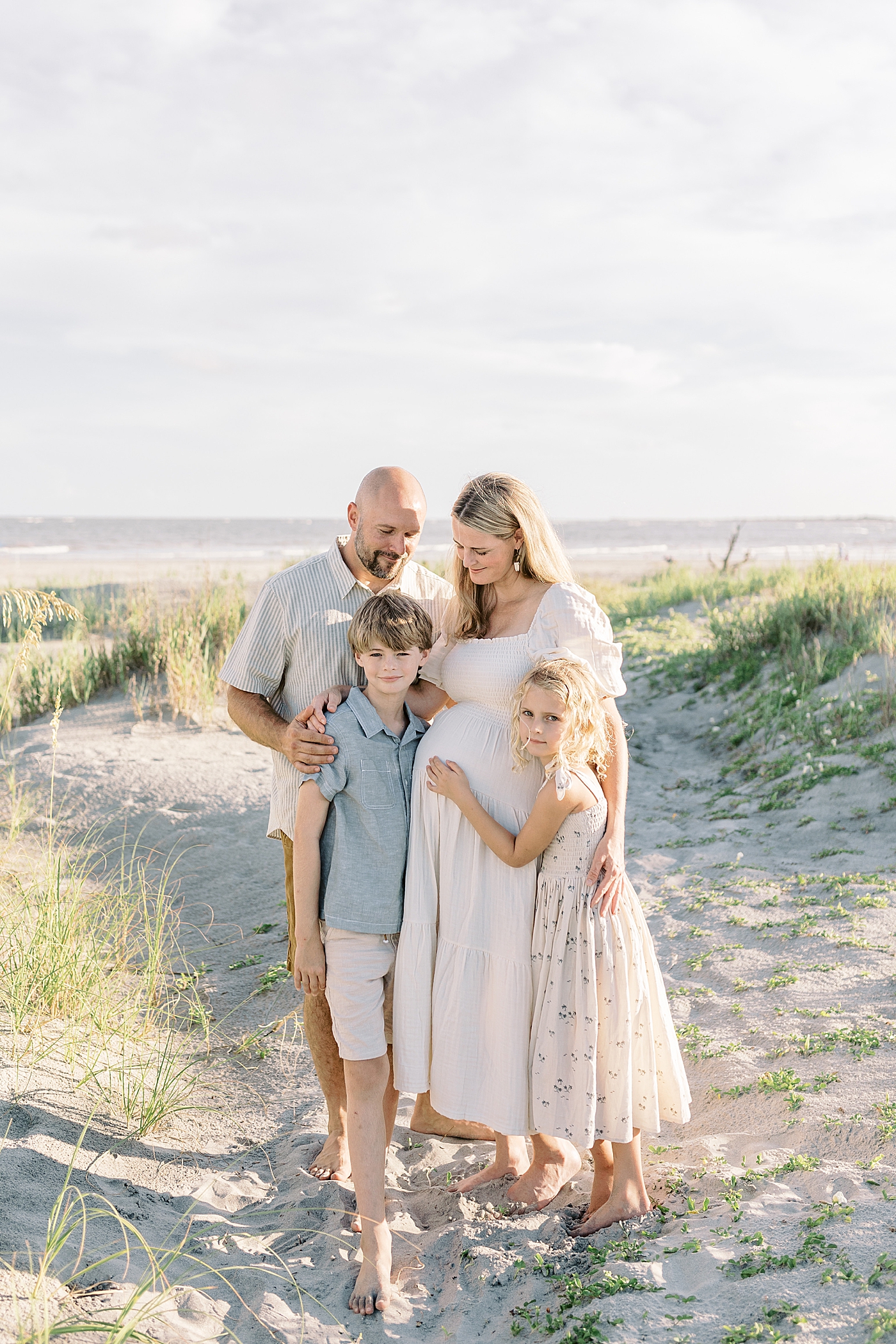 Family of four snuggling at the beach | Image by Caitlyn Motycka