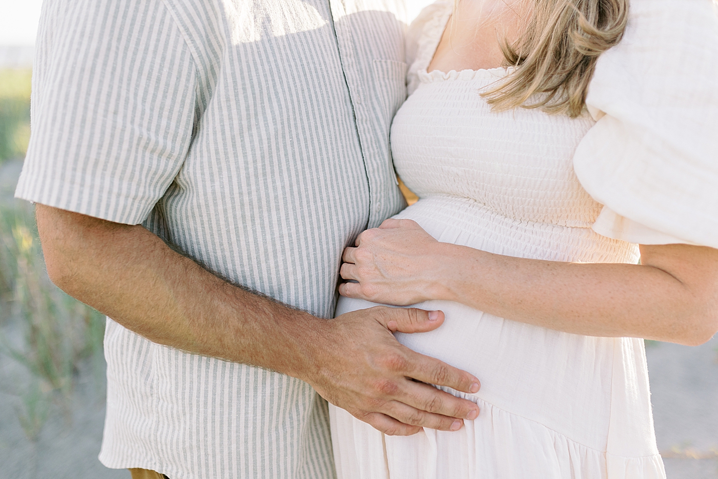 Detail of mom and dad's hands on mom's pregnant belly | Image by Caitlyn Motycka