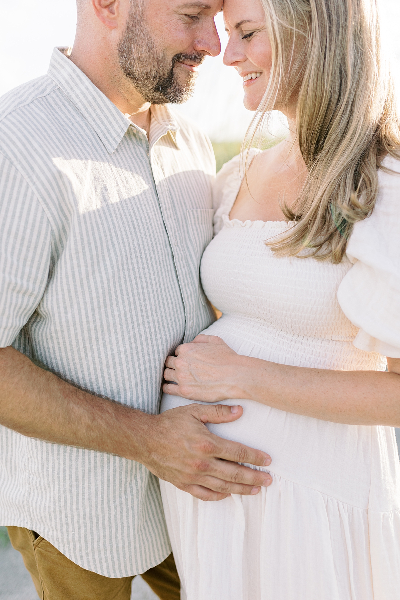 Detail of mom and dad snuggling during their Maternity Session at Folly Beach | Image by Caitlyn Motycka