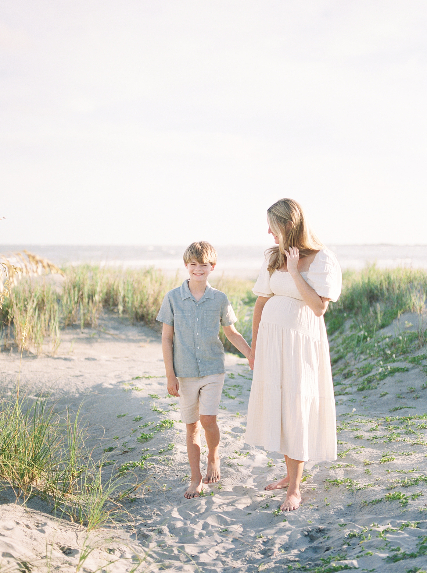 Mom and little boy holding hands on the beach during their Maternity Session at Folly Beach | Image by Caitlyn Motycka