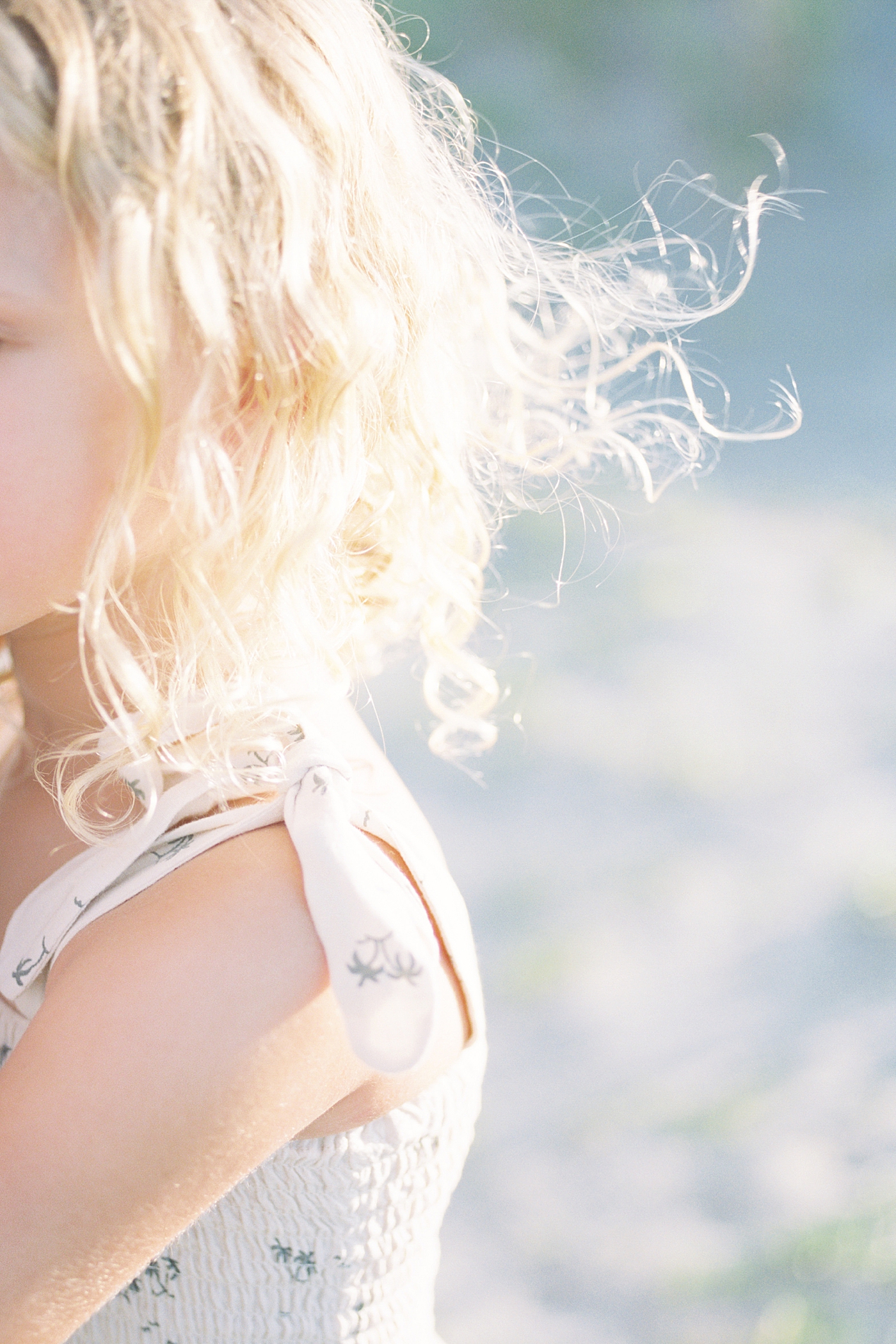 Detail of little girl's blonde hair blowing over her shoulder | Image by Caitlyn Motycka