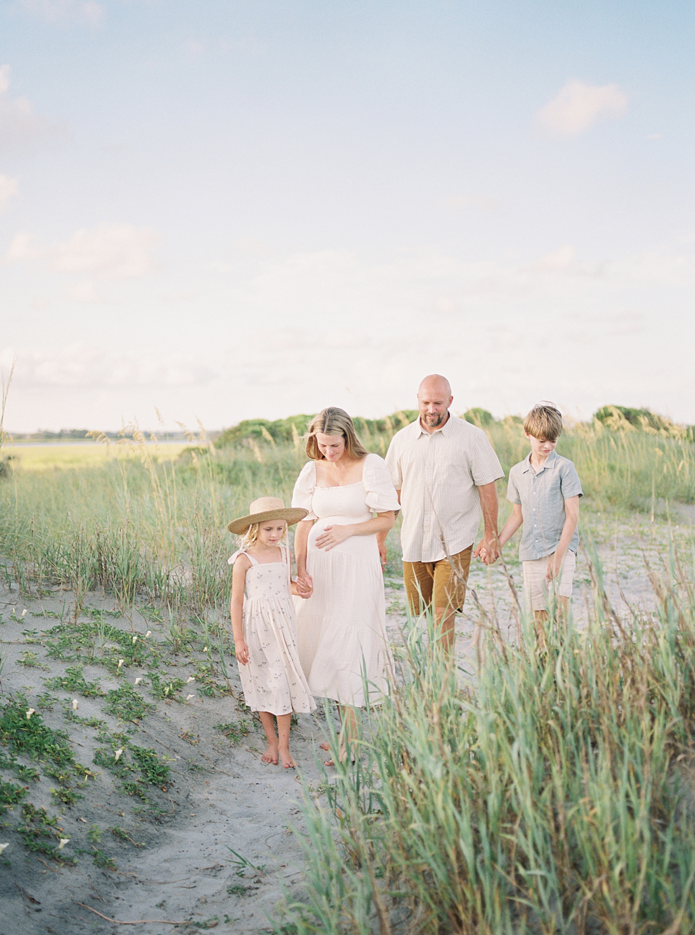 Family of four walking holding hands during their Maternity Session at Folly Beach | Image by Caitlyn Motycka