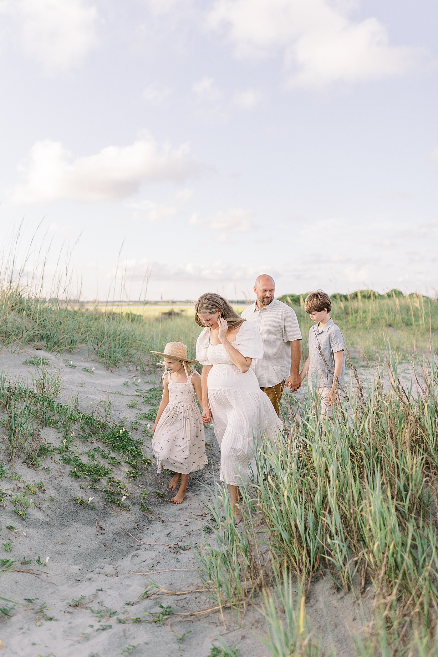 Family of four walking to the beach while holding hands | Image by Caitlyn Motycka
