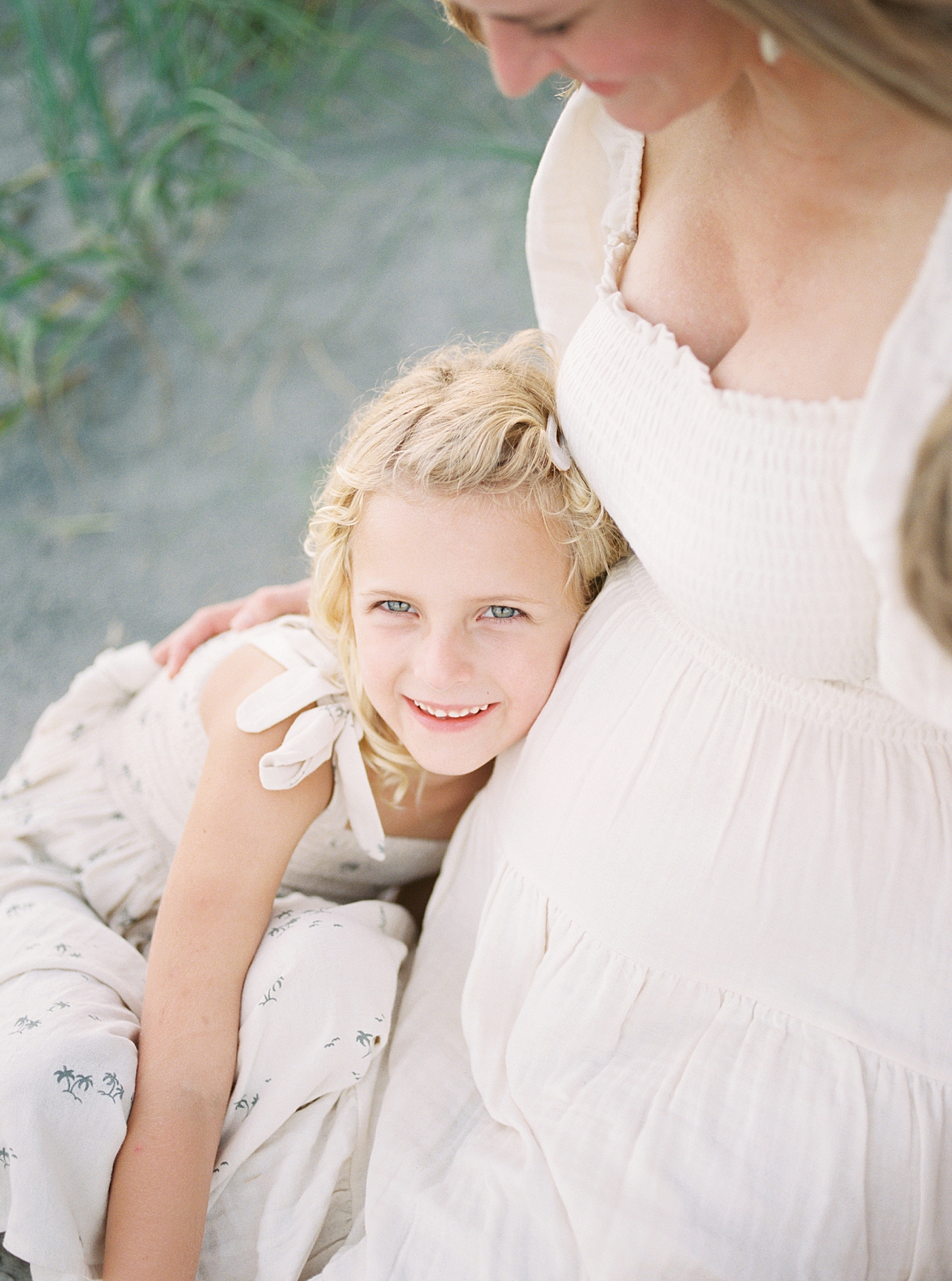 Detail of little girl smiling and hugging her mom during their Maternity Session at Folly Beach | Image by Caitlyn Motycka