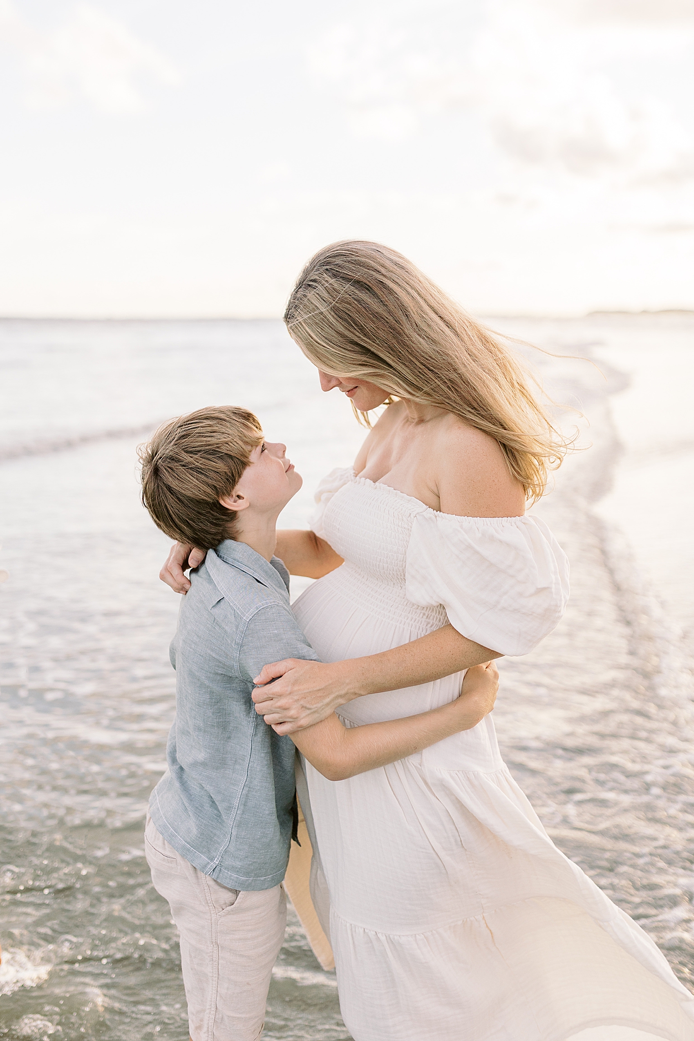 Little boy and mom interacting on the beach during maternity session | Image by Caitlyn Motycka