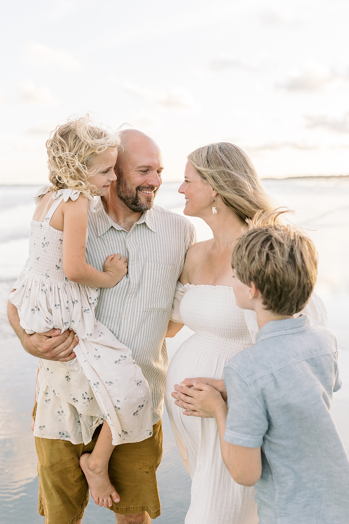 Family of four snuggling together during their Maternity Session at Folly Beach | Image by Caitlyn Motycka