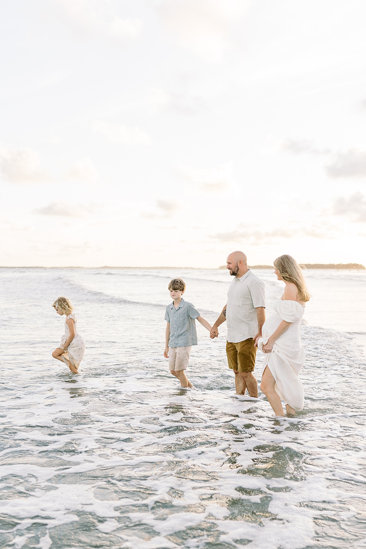 Family of four playing in the ocean during maternity session | Image by Caitlyn Motycka