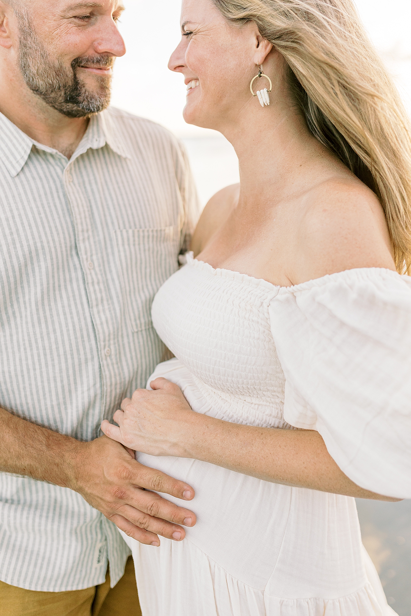 Detail of mom and dad to be holding mom's belly | Image by Caitlyn Motycka