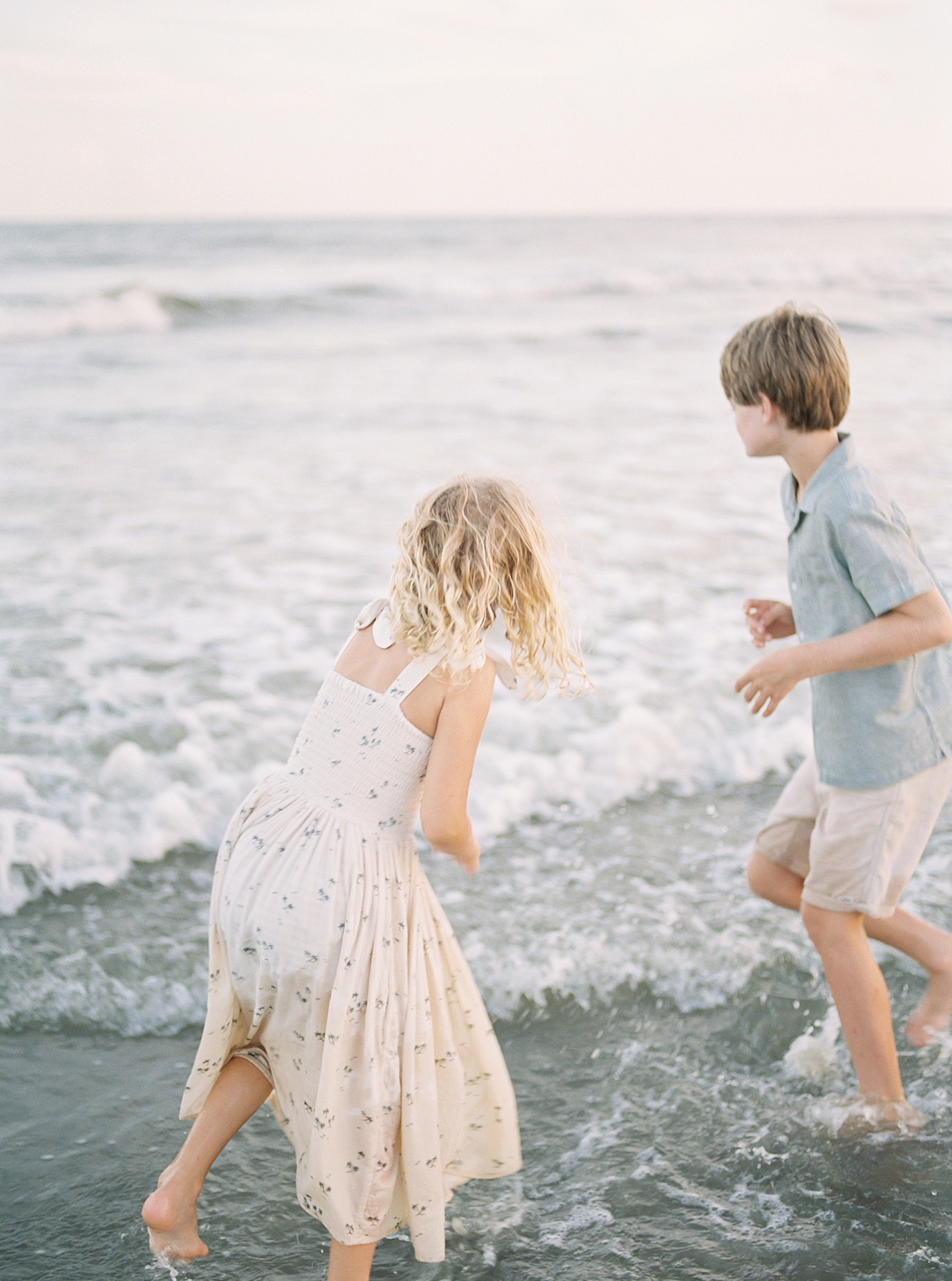 Brother and sister playing in the ocean during their Maternity Session at Folly Beach | Image by Caitlyn Motycka