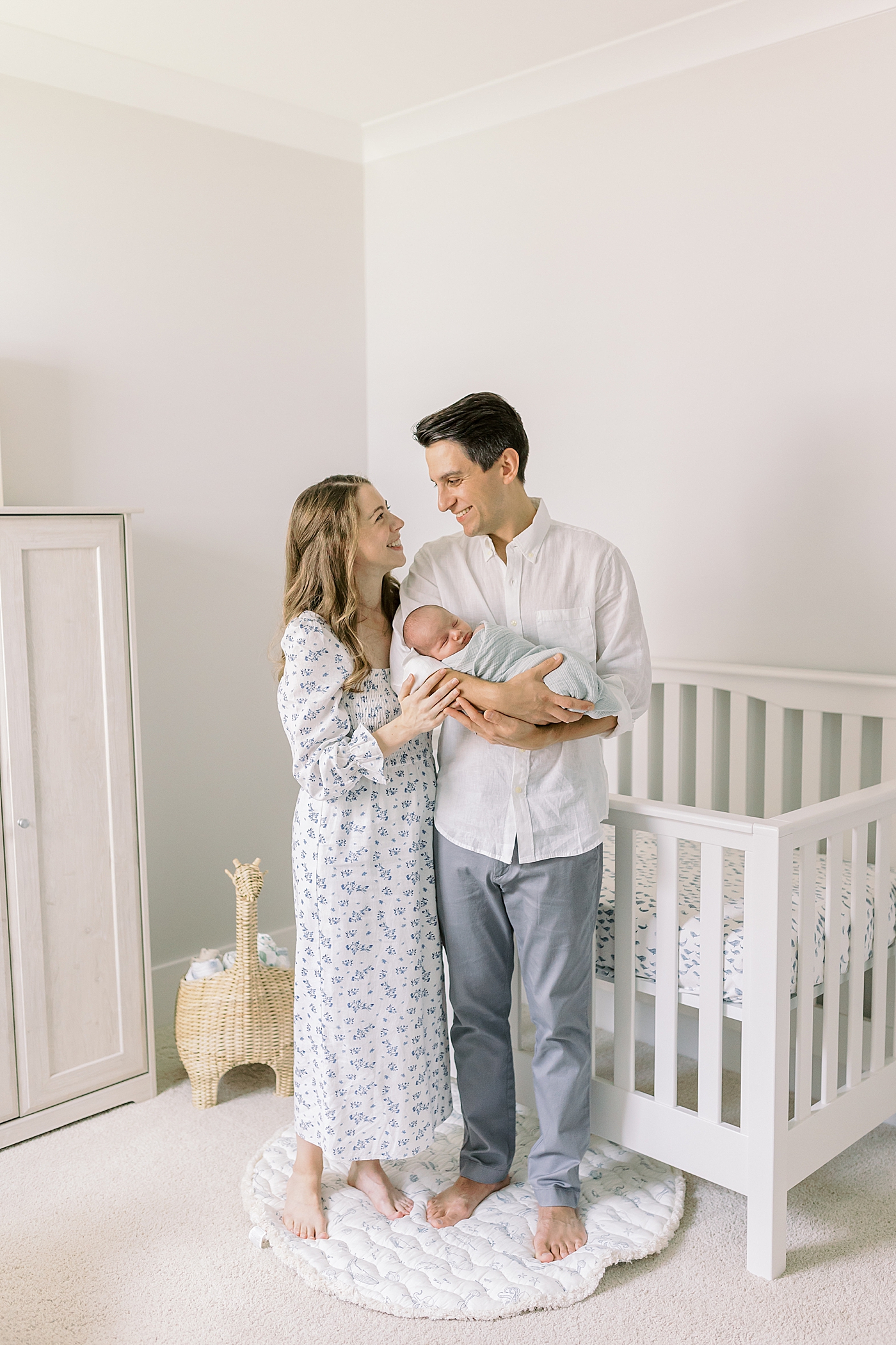 Mom and dad holding their baby in nursery during lifestyle newborn photos | Image by Caitlyn Motycka