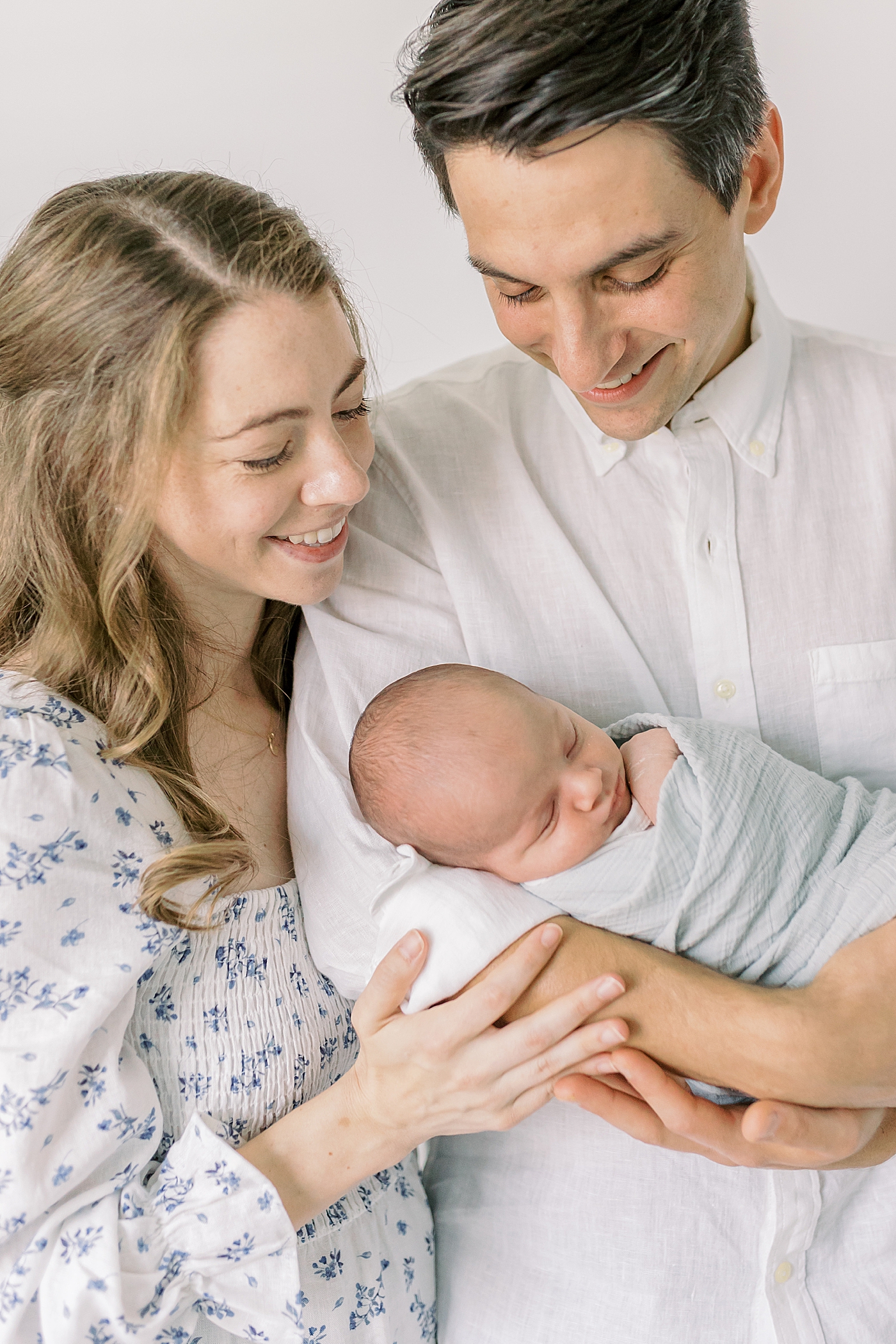 Detail of mom and dad holding their newborn baby and smiling | Image by Caitlyn Motycka